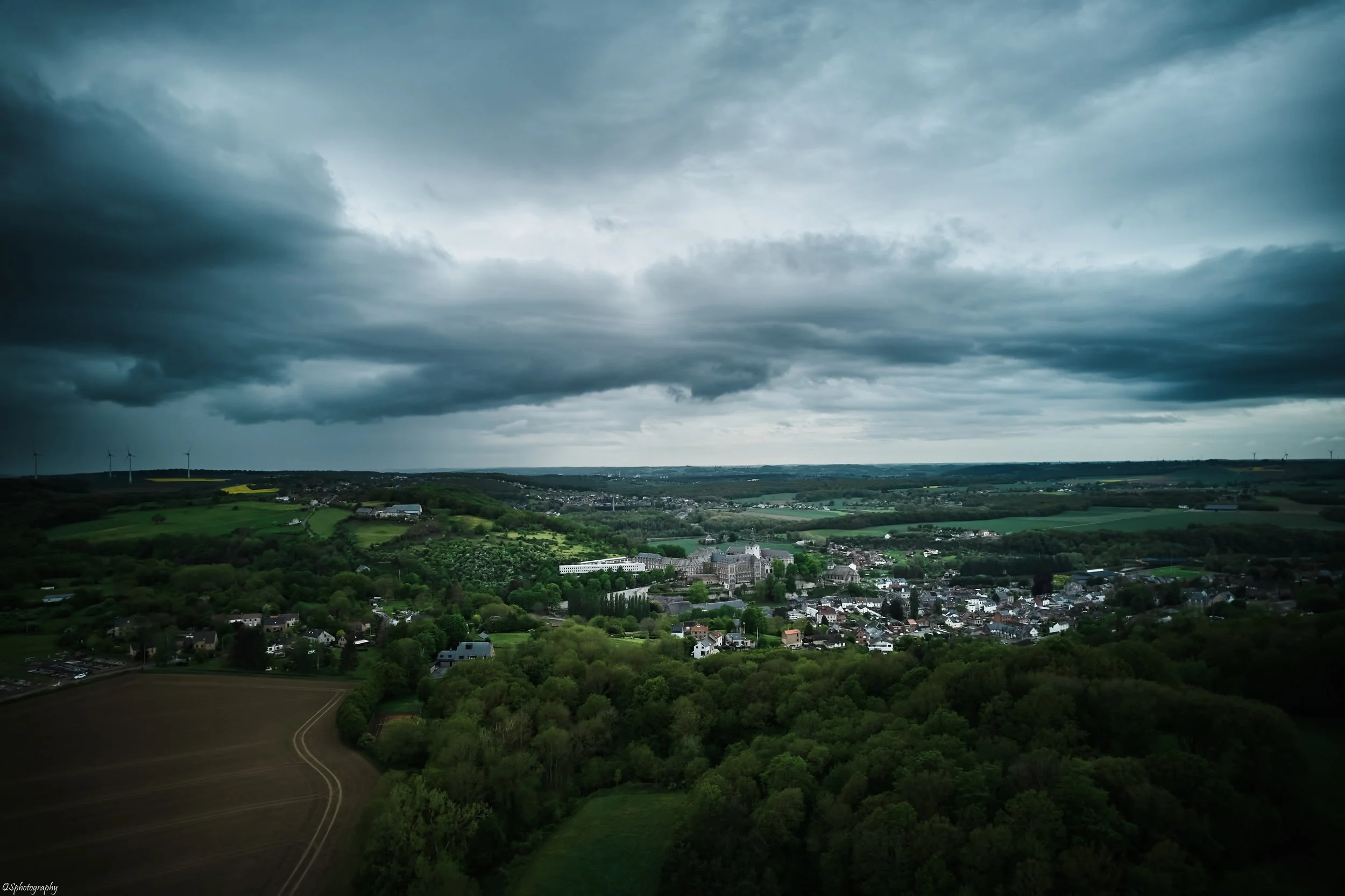 Paysage rural avec une ville, un château, des forêts et des champs, sous un ciel nuageux. | QSphotography | Namur