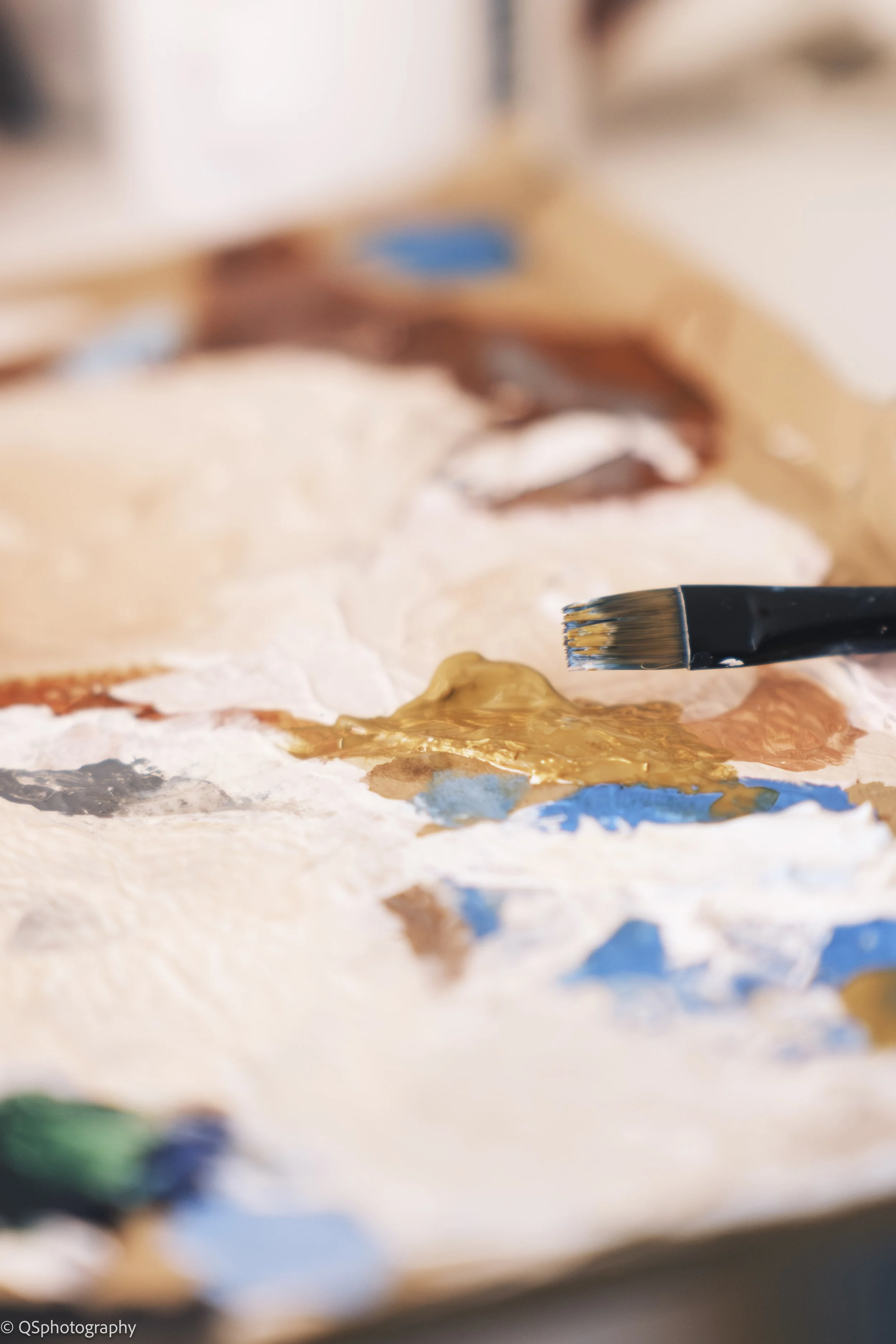 Pinceau trempant dans de la peinture de différentes couleurs sur une palette d'artiste.