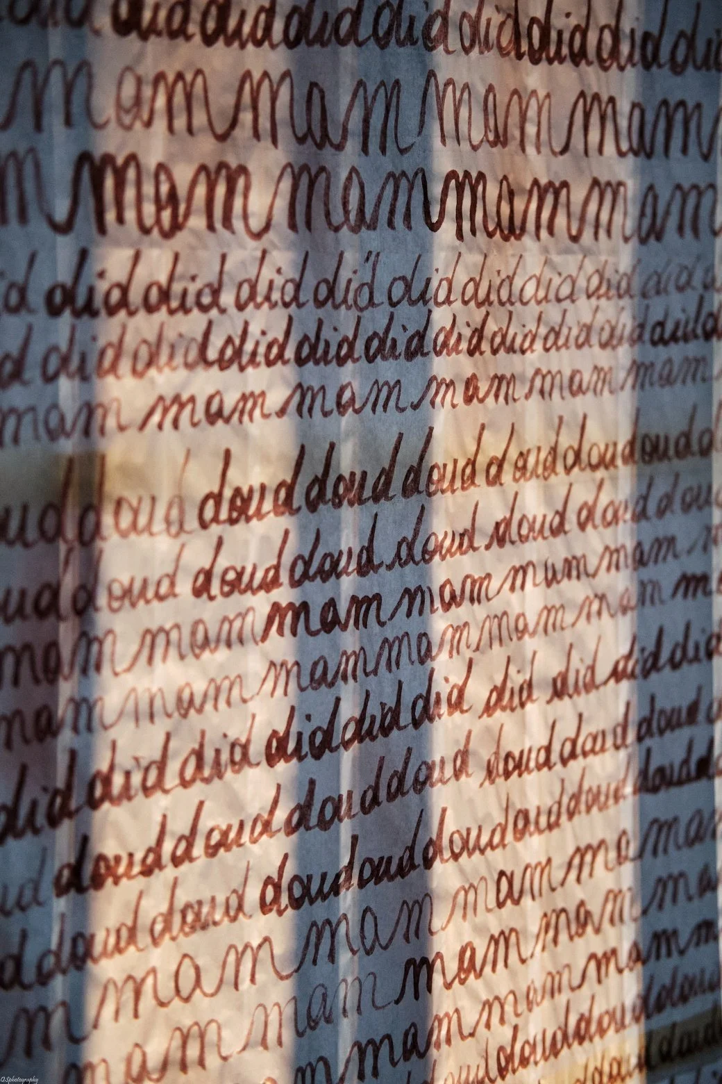 Une surface couverte de mots écrits en différentes couleurs et styles, comprenant principalement le mot "maman" et la phrase "did did".