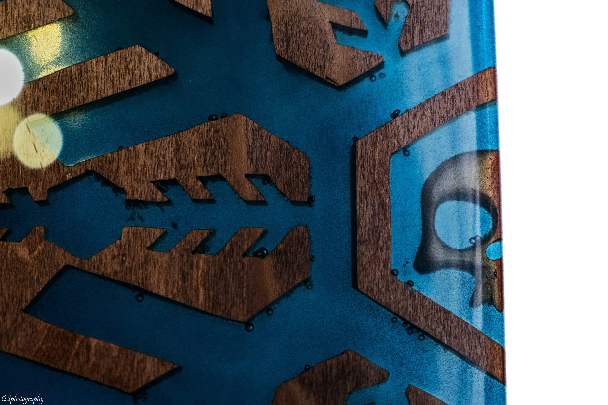 Une surface en bois (Skate) avec de la peinture bleue, des découpes en forme de flocons de neige et un symbole d'ours en peluche dans une vitrine. | QSphotography | Namur