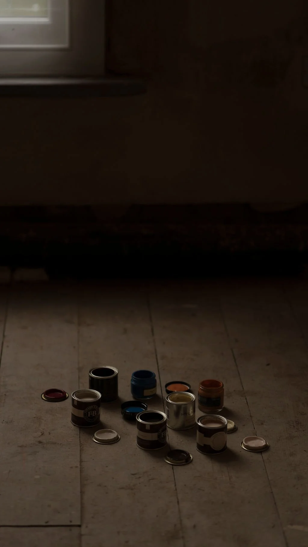 A collection of open paint cans and lids scattered on a floor.