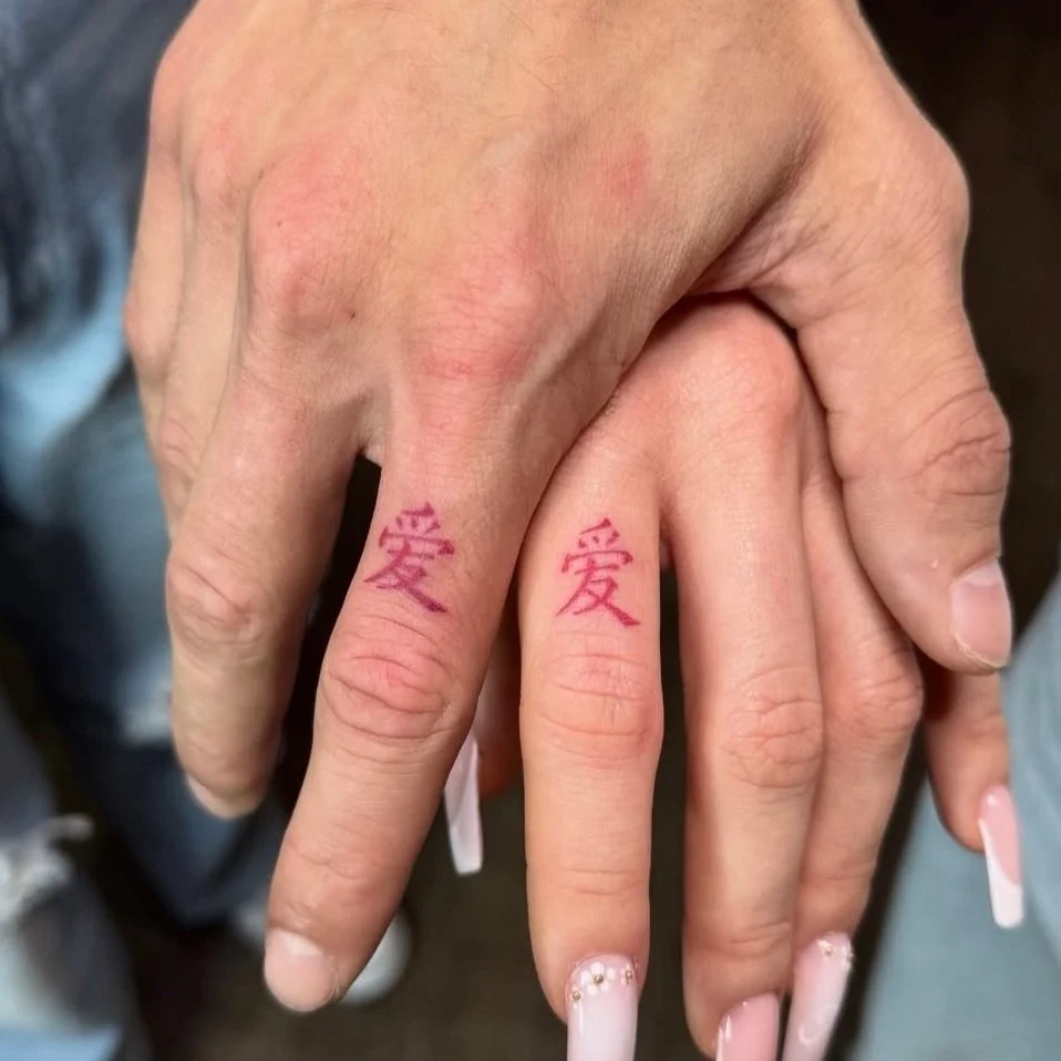 Zwei Hände mit pinken Tätowierungen der chinesischen Zeichen für Liebe.
