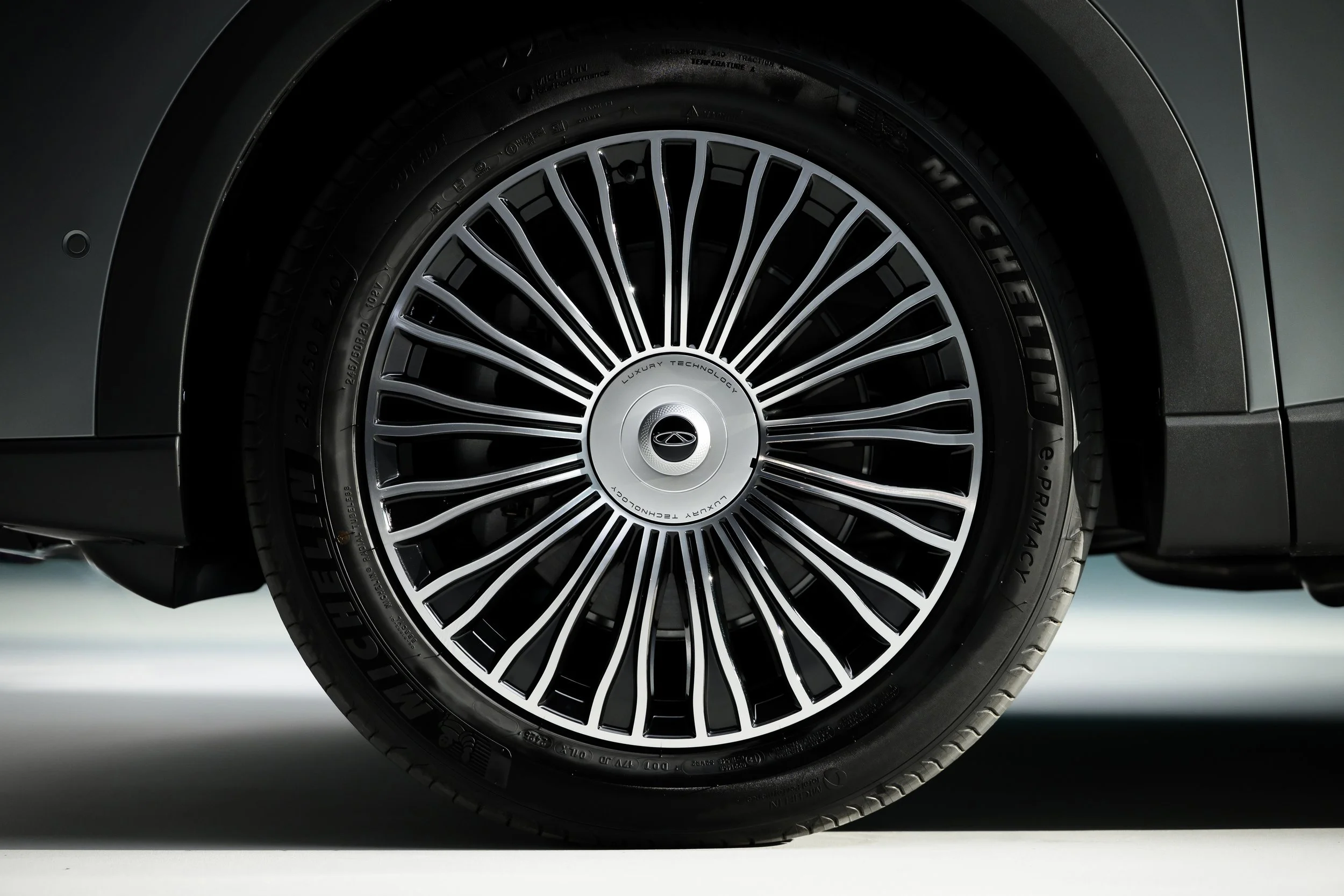Close-up of a luxury car's wheel with a detailed rim and tire, showing the vehicle's sleek design.