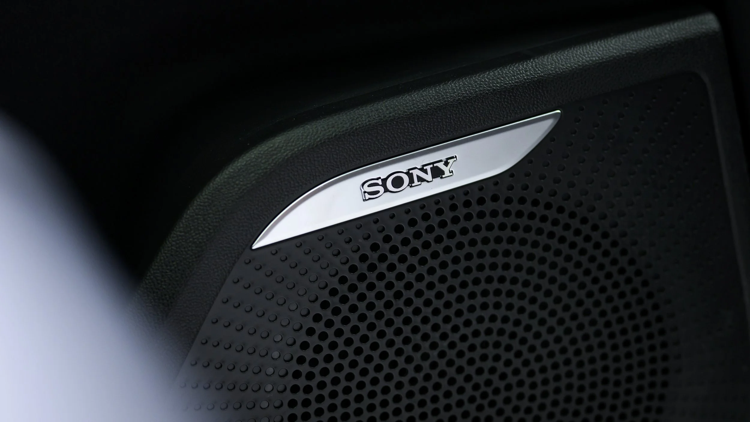 Close-up of a black Sony speaker with a silver Sony logo and circular perforations.