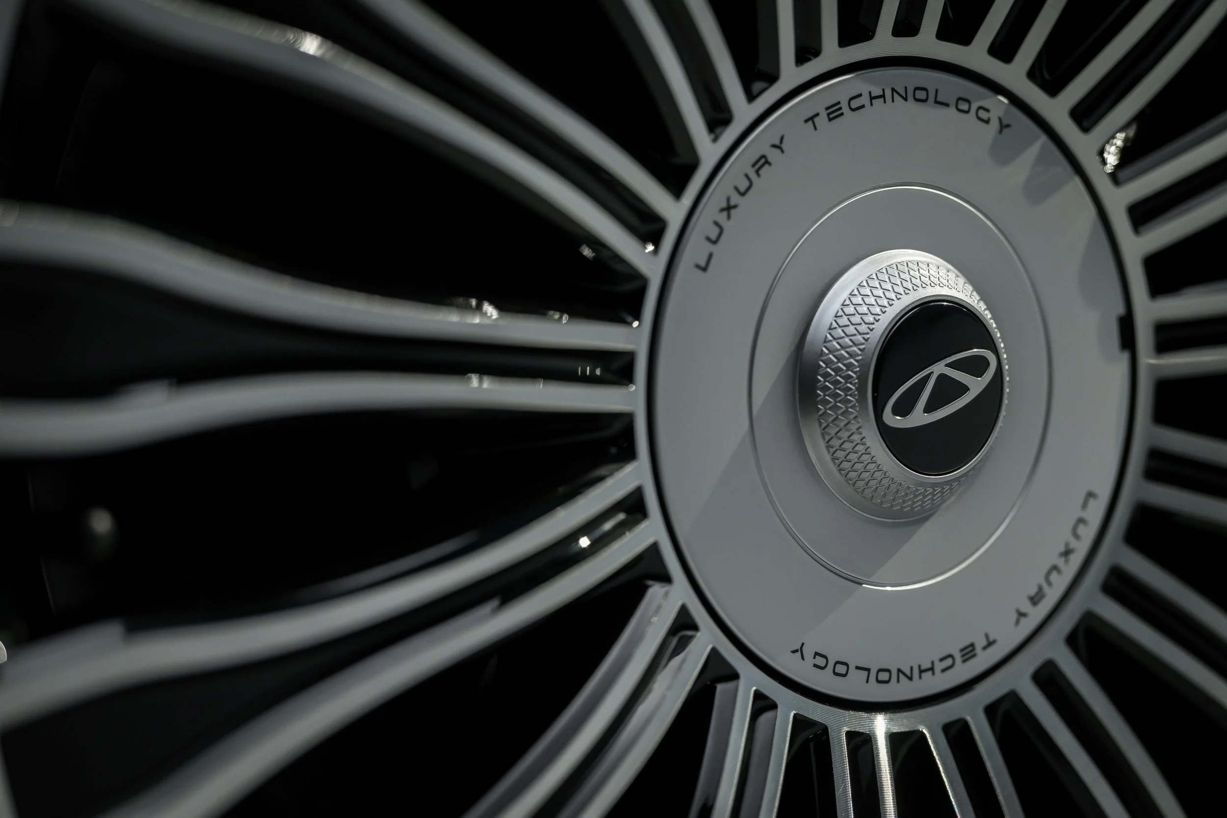 Close-up of a luxury car wheel rim with the Hyundai logo, featuring silver spokes and the words 'Luxury Technology' engraved on the rim.