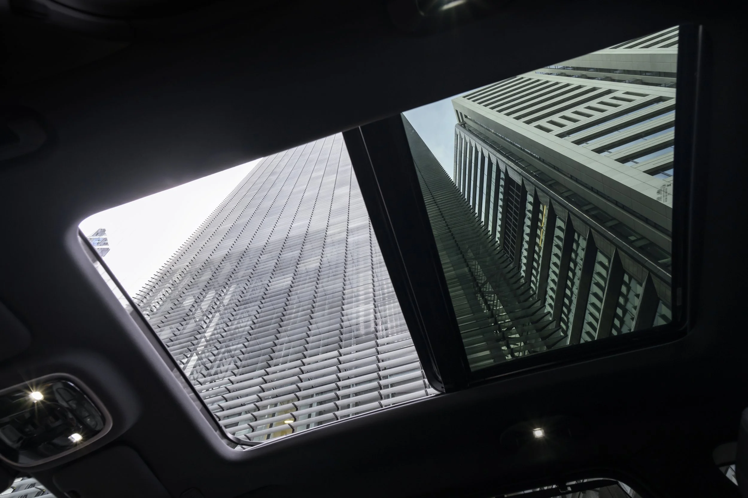 View looking up at skyscrapers through a car's sunroof.