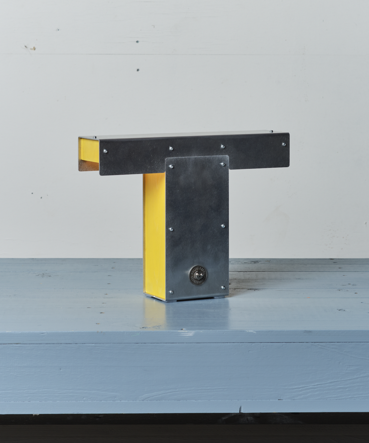 A black and yellow T-shaped object on a light blue wooden surface.