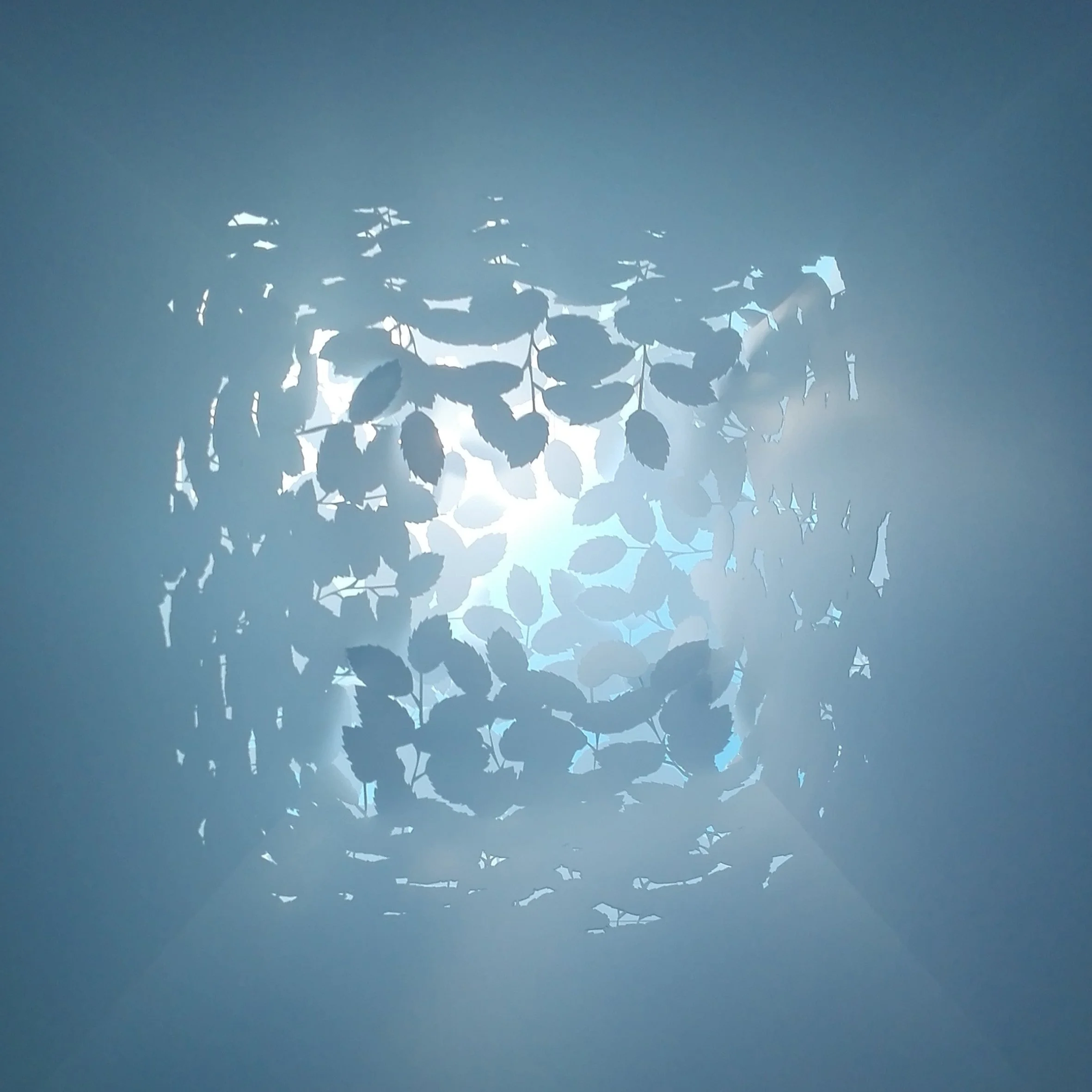 Light fixture with a decorative shade made of cut-out leaf shapes, emitting light.