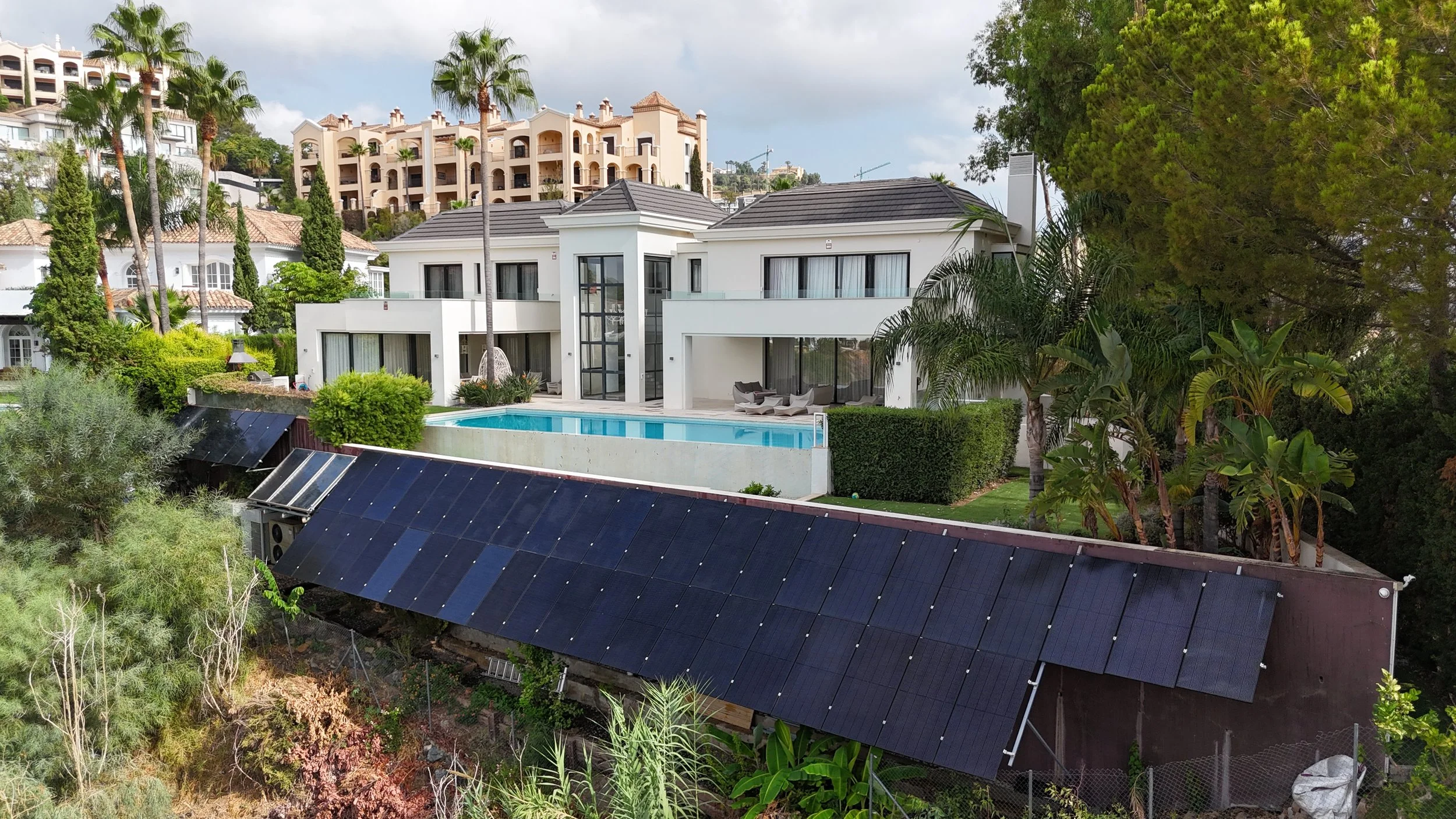 Casa moderna con piscina, jardines y paneles solares en un entorno verde y residencial en las colinas.