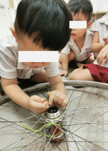 Toddler independently practising fine motor skills using a cable tie.