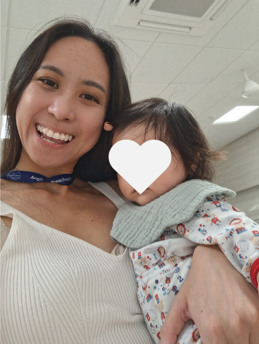 Hermes Lu carrying a young infant and smiling.