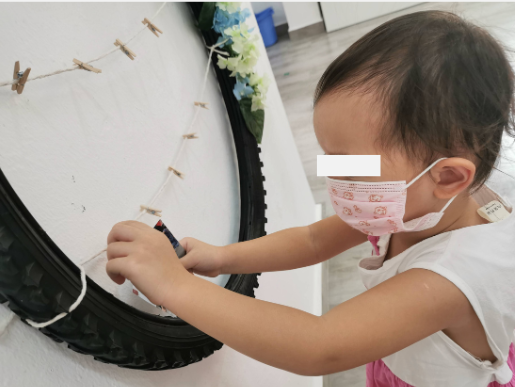 Child attaching a photograph to a photo frame made from a recycled bicycle tyre.