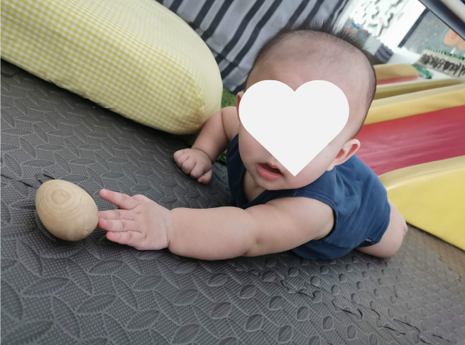 Baby practising tummy time while reaching towards a toy.