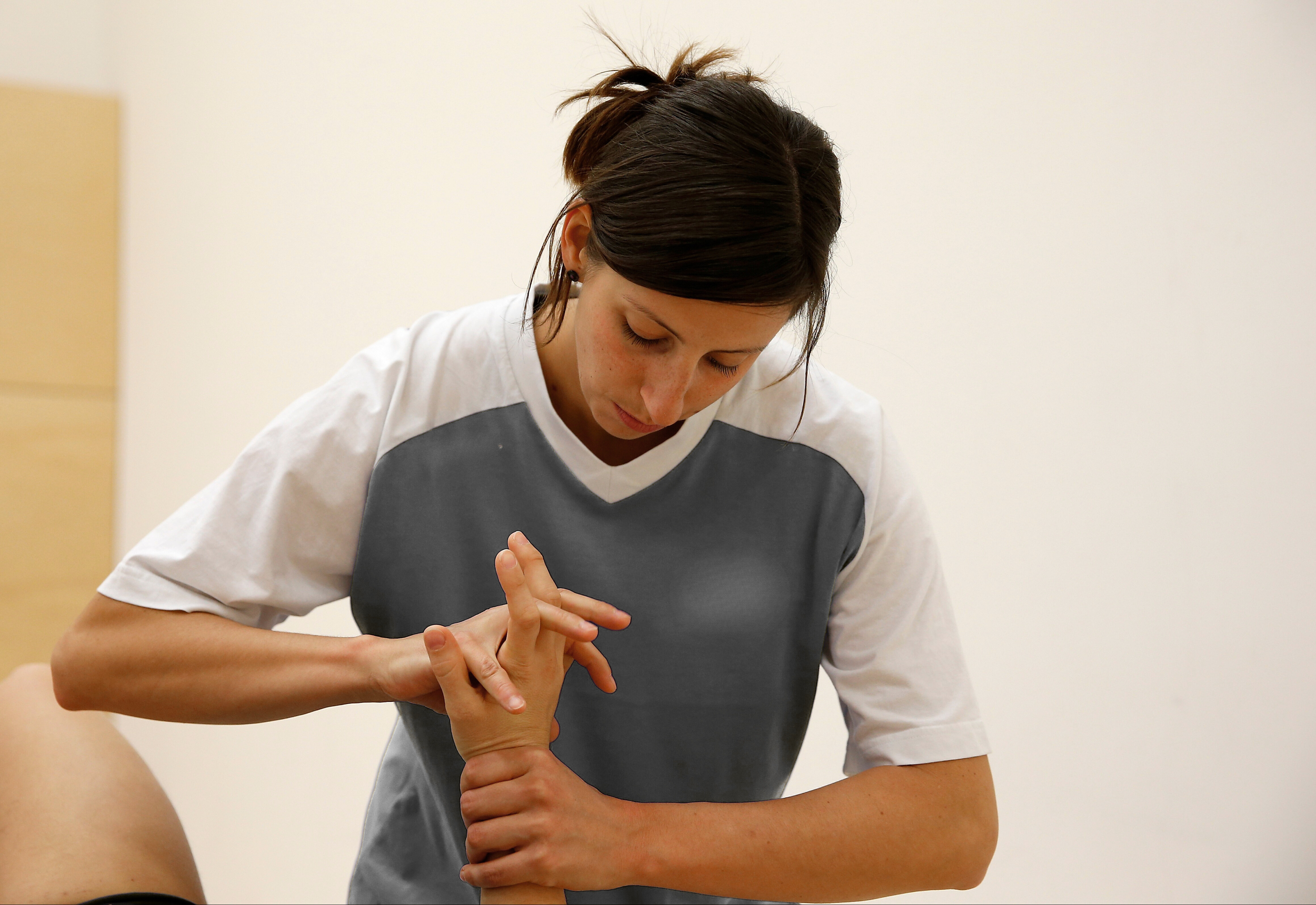 Physiotherapeutin behandelt Hand eines Patienten in einer Praxis.