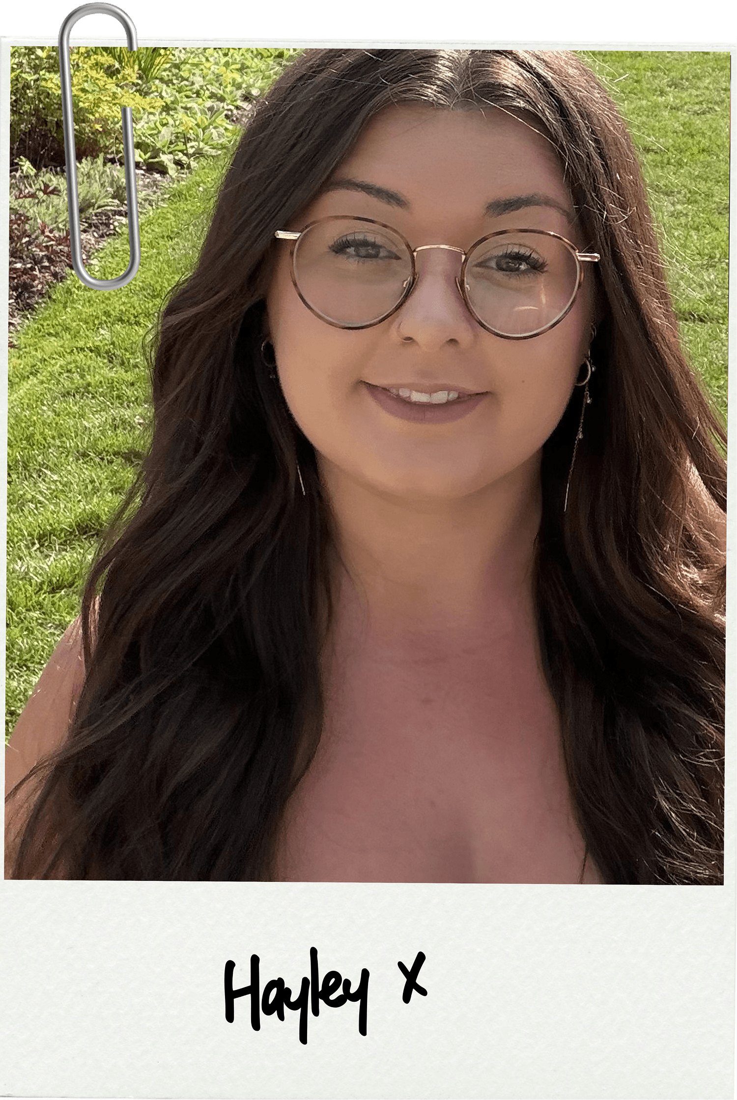 A woman with long dark hair, glasses, and earrings smiling outdoors with green grass and plants in the background, labeled 'Hayley x'.