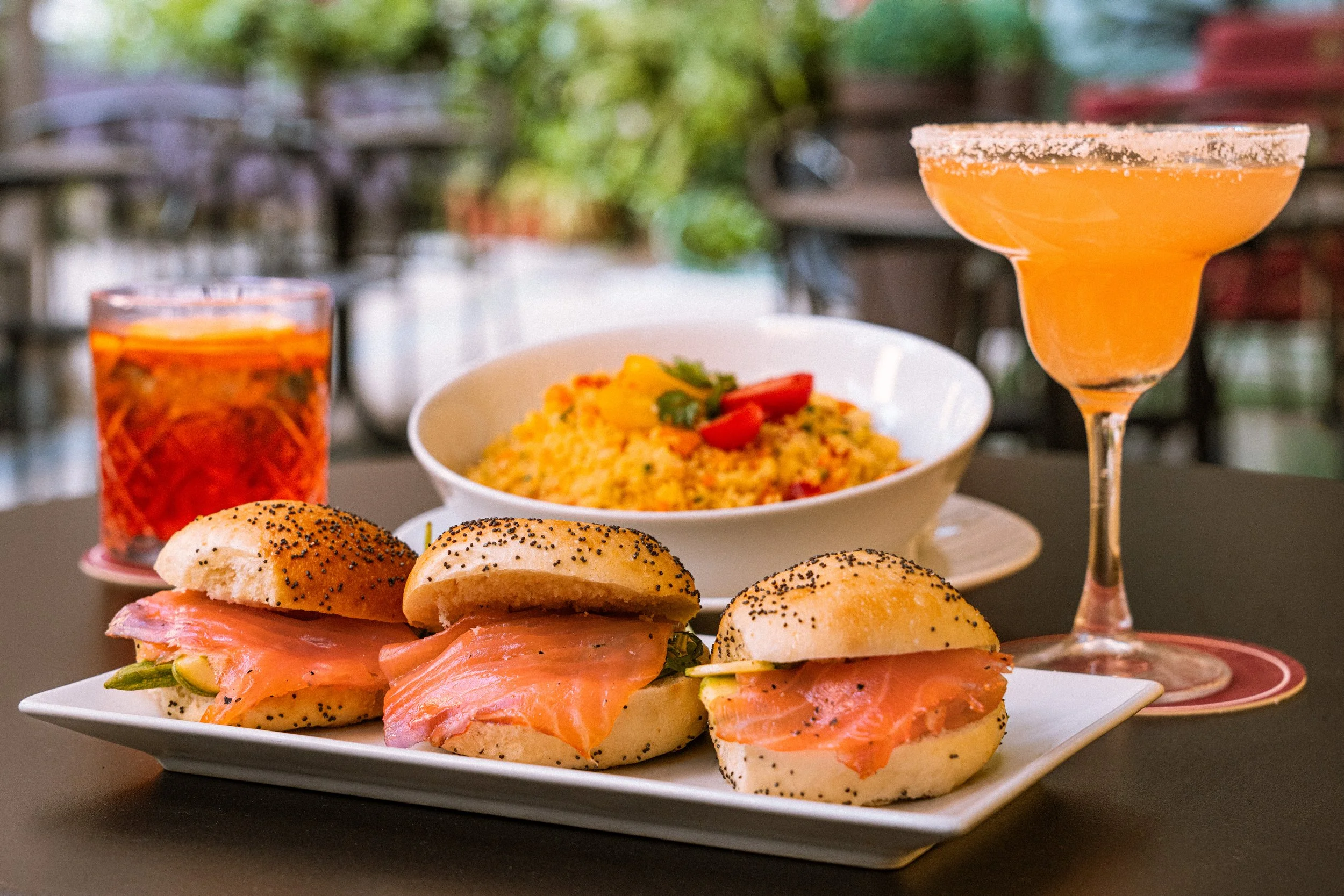Panini con salmone e piatto di cous cous con cocktail colorati in location immersa nel verde Amaranto bar Parioli 