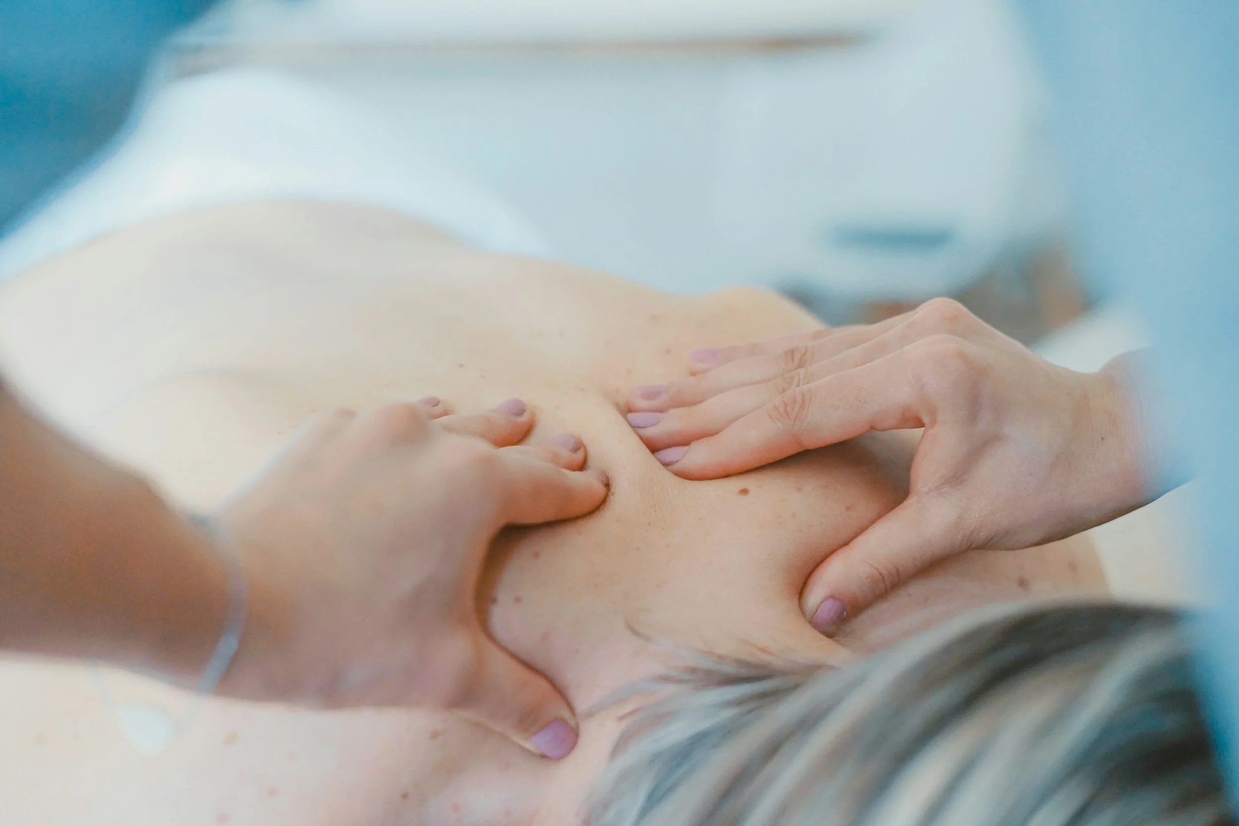 Close-up of a person receiving a massage on their back with hands applying pressure.