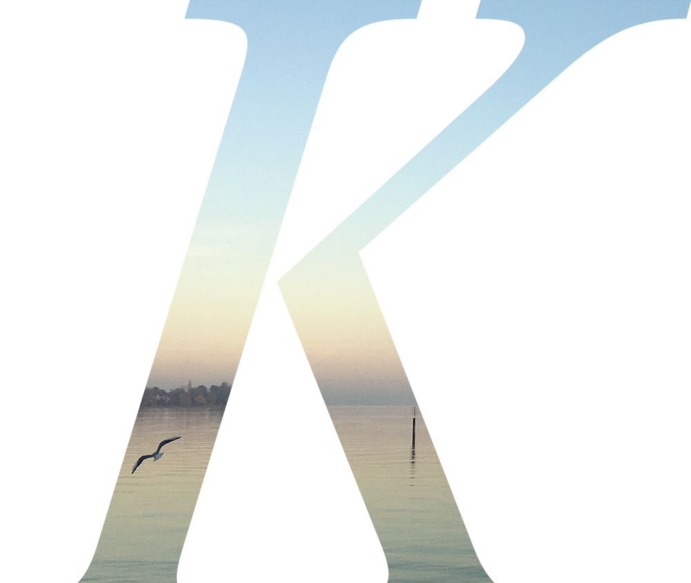 Buchstabe K im Hintergrund ein Bild vom Bodensee in Abenddämmerung mit Möwe.