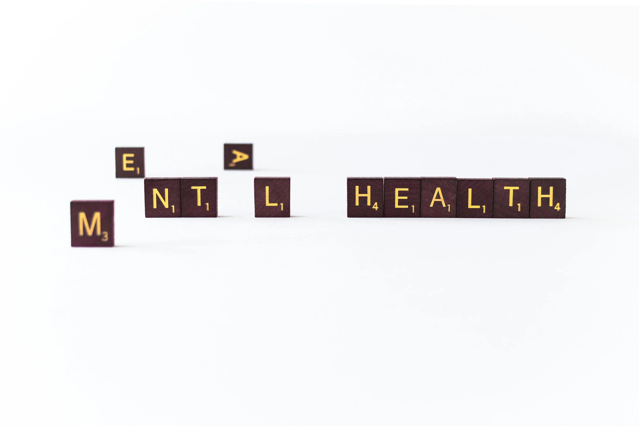 Scrabble tiles arranged to spell 'MENTAL HEALTH' on a white background.