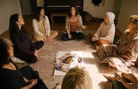A group of women sitting in a circle on the floor having a discussion.