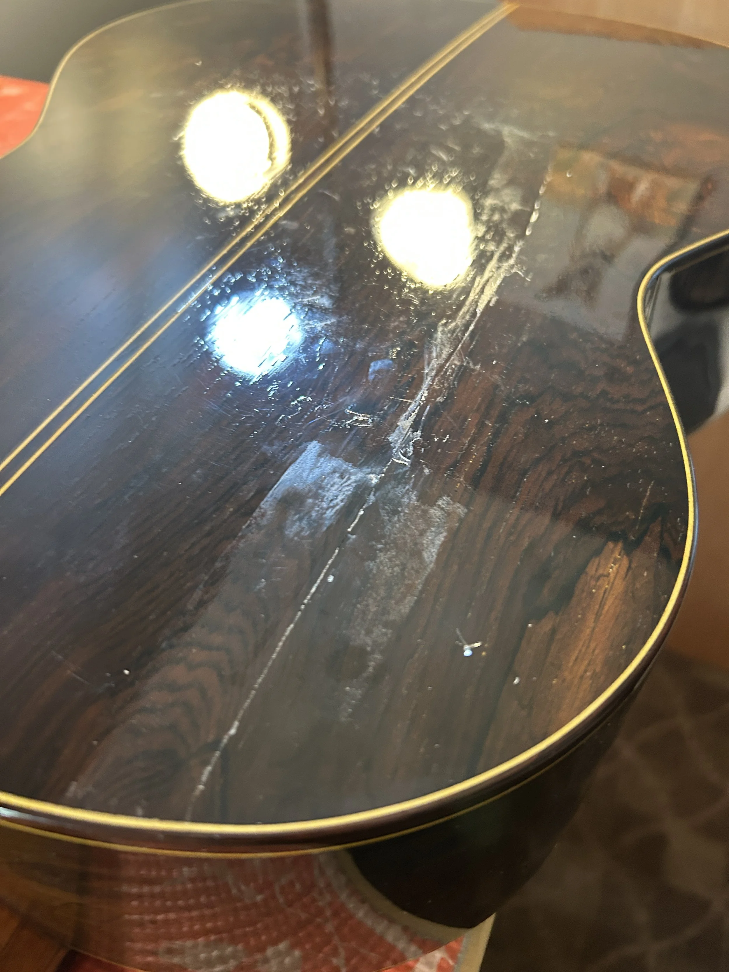 The back of a wooden acoustic guitar with a crack bring glued.