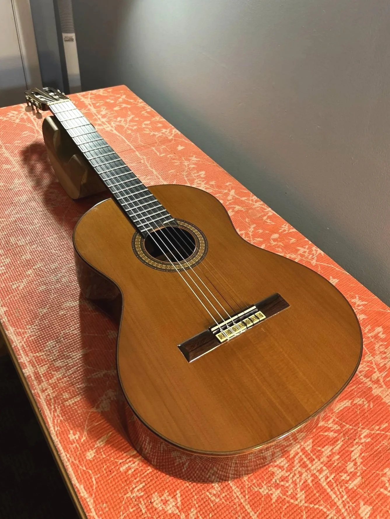 A classical guitar laying on top of a bench