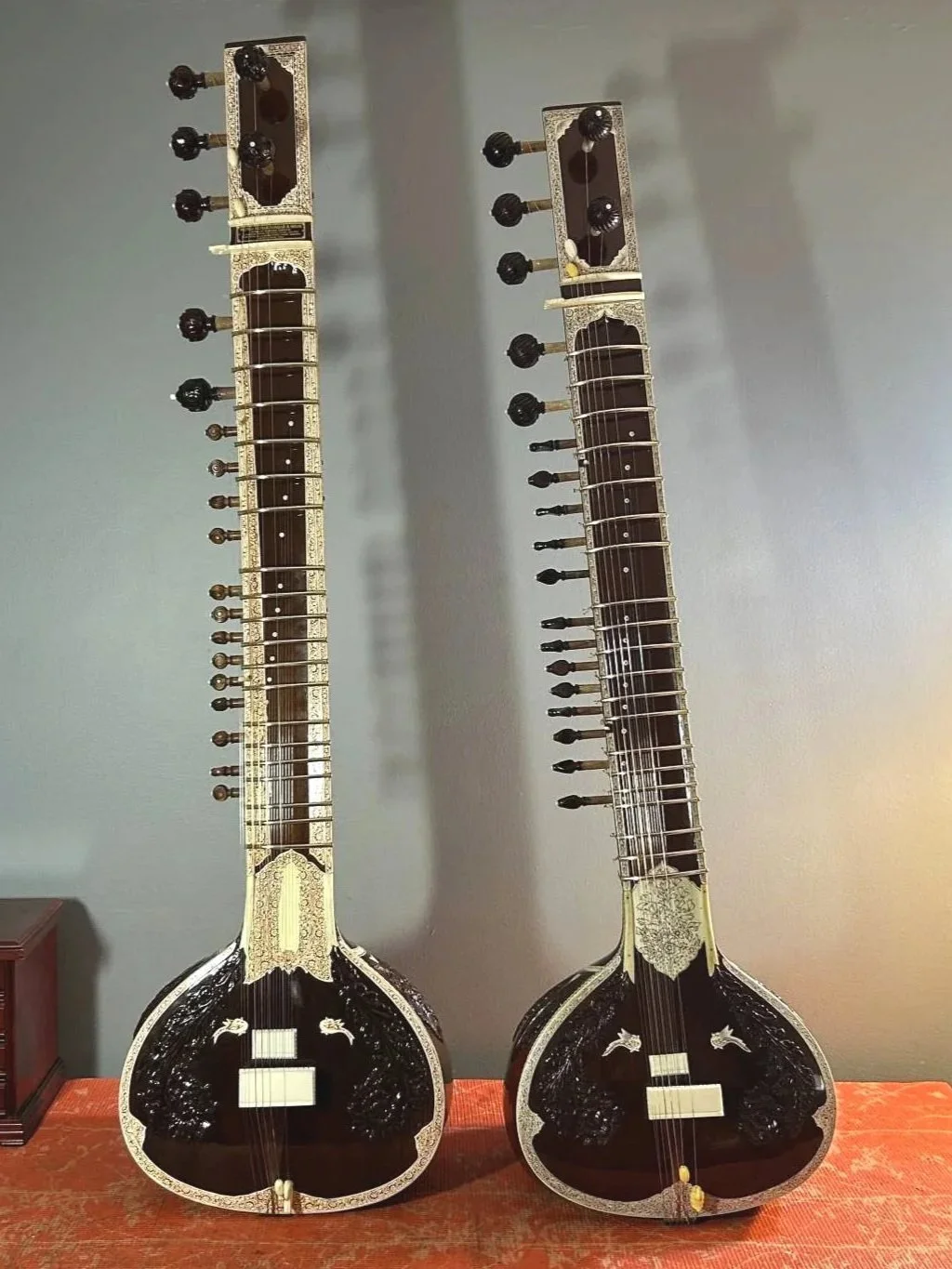 2 sitars standing o top of a work bench