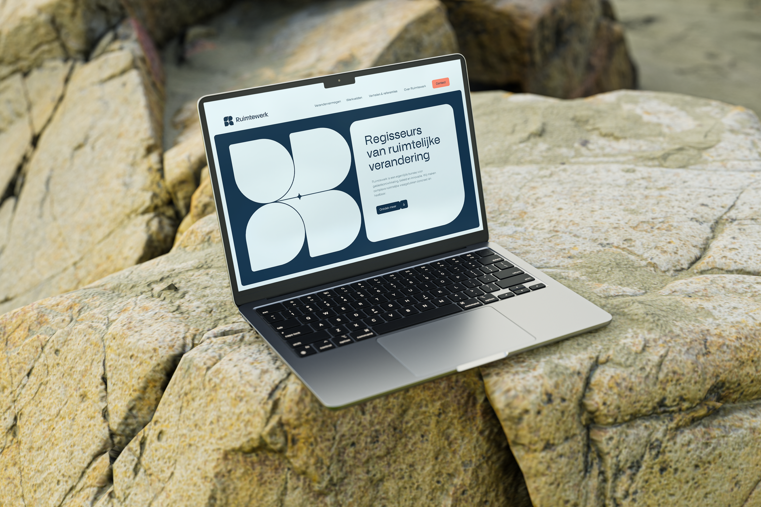 A laptop on a large rock outdoors displaying a website in Dutch about spatial transformation.