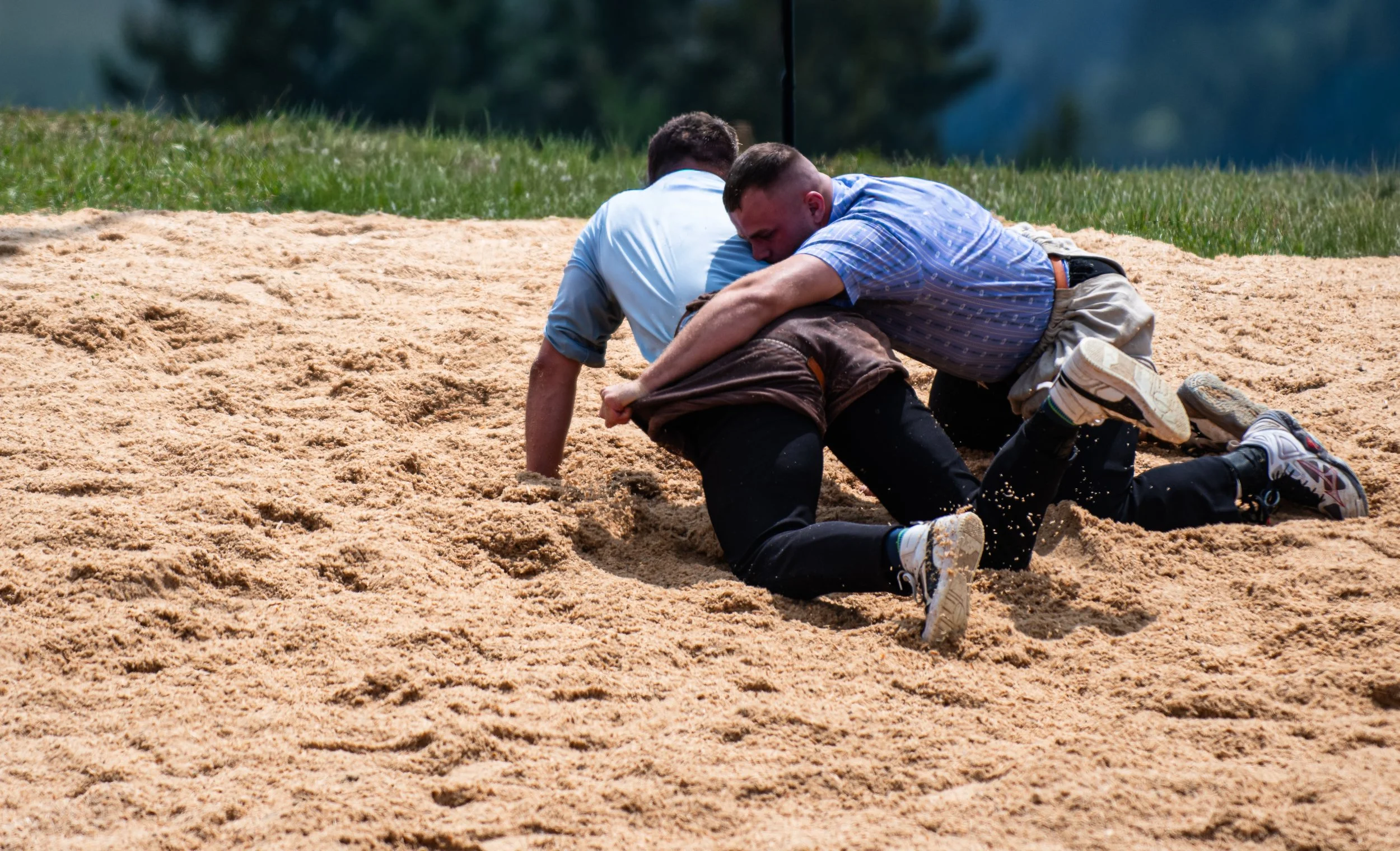 Zwei Männer im Anzug in einem Sandkasten kämpfen im Freien