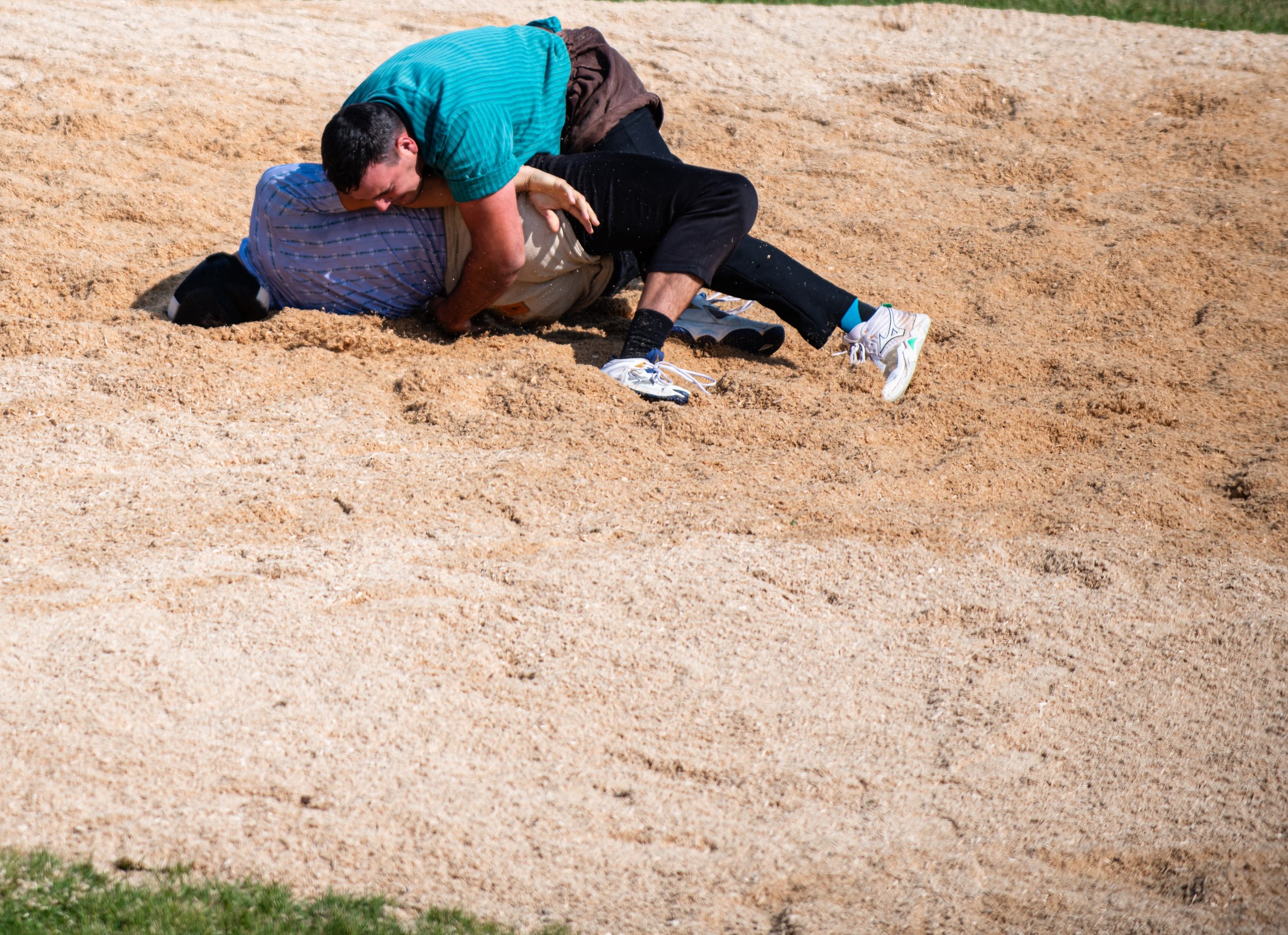 Zwei Männer liefern sich einen Kampf auf einem Sandplatz