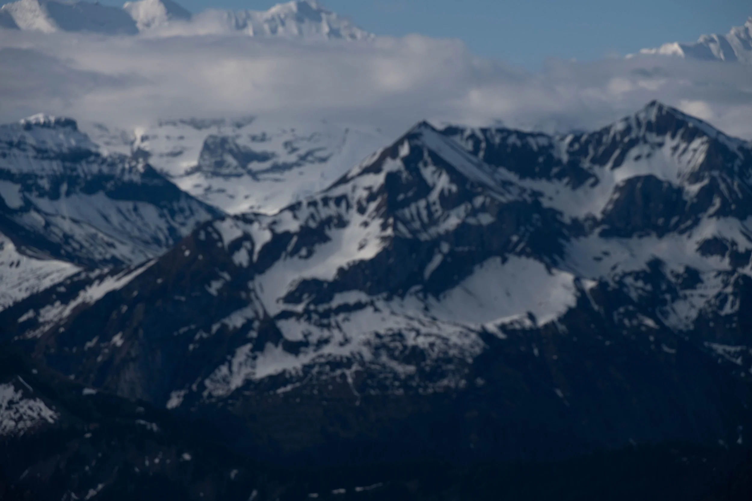 Schneebedeckte Berge unter einem bewölkten Himmel in einer Berglandschaft.