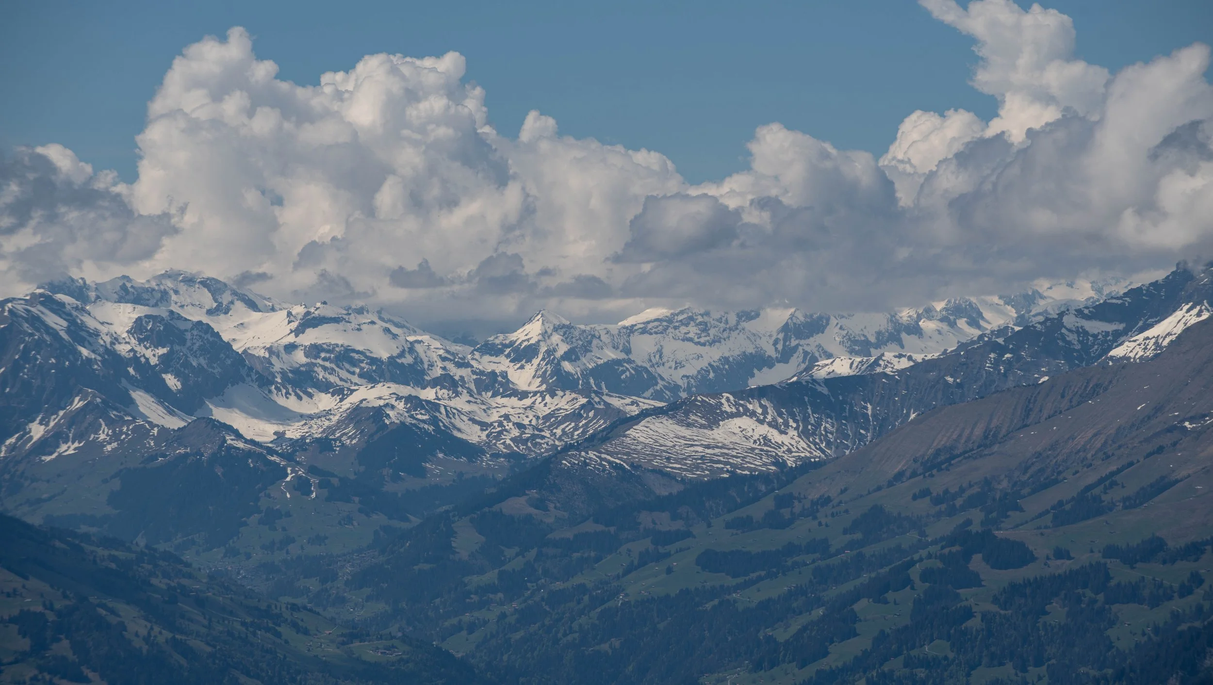 Bergkette mit schneebedeckten Gipfeln unter bewölktem Himmel in den Alpen.
