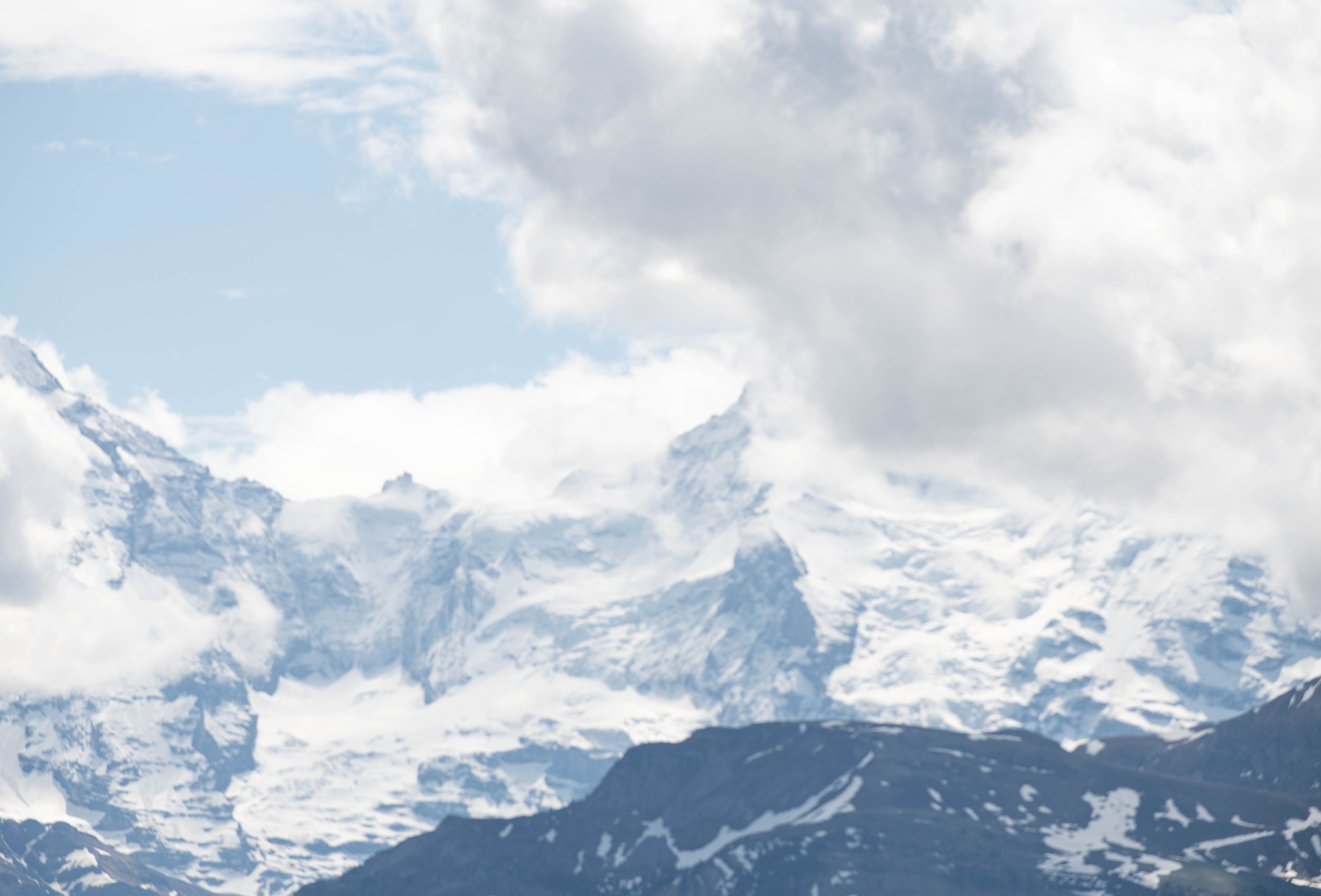 Schneebedeckte Berge unter bewölktem Himmel in den Alpen.