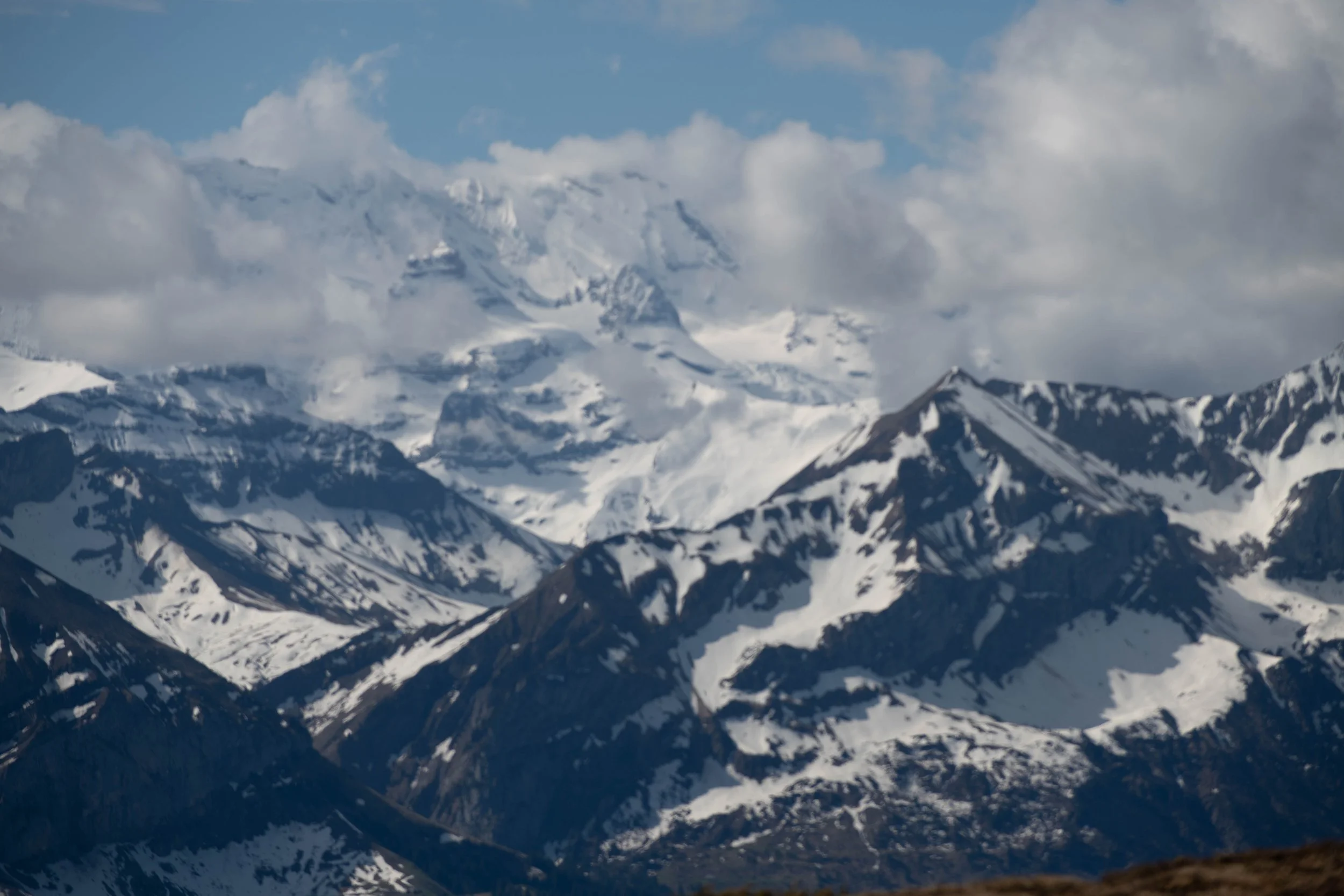 Bergwelt mit schneebedeckten Gipfeln und teilweise bewölktem Himmel