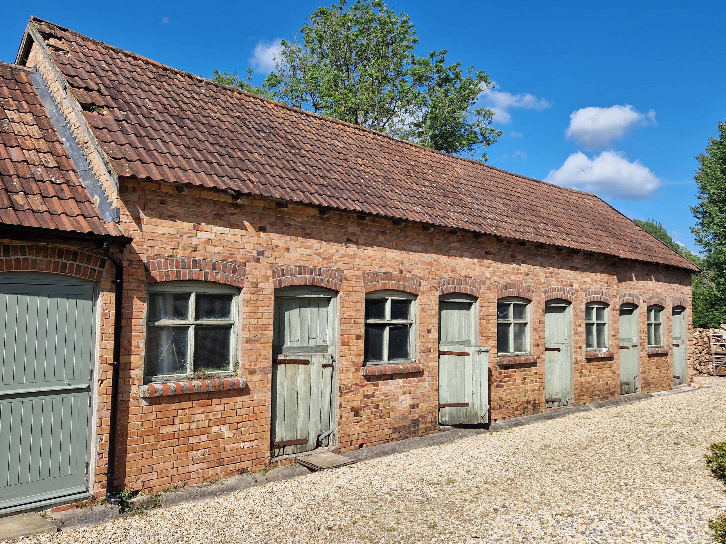 Brickwork barn with single storey roof, timber doors and windows in the countryside