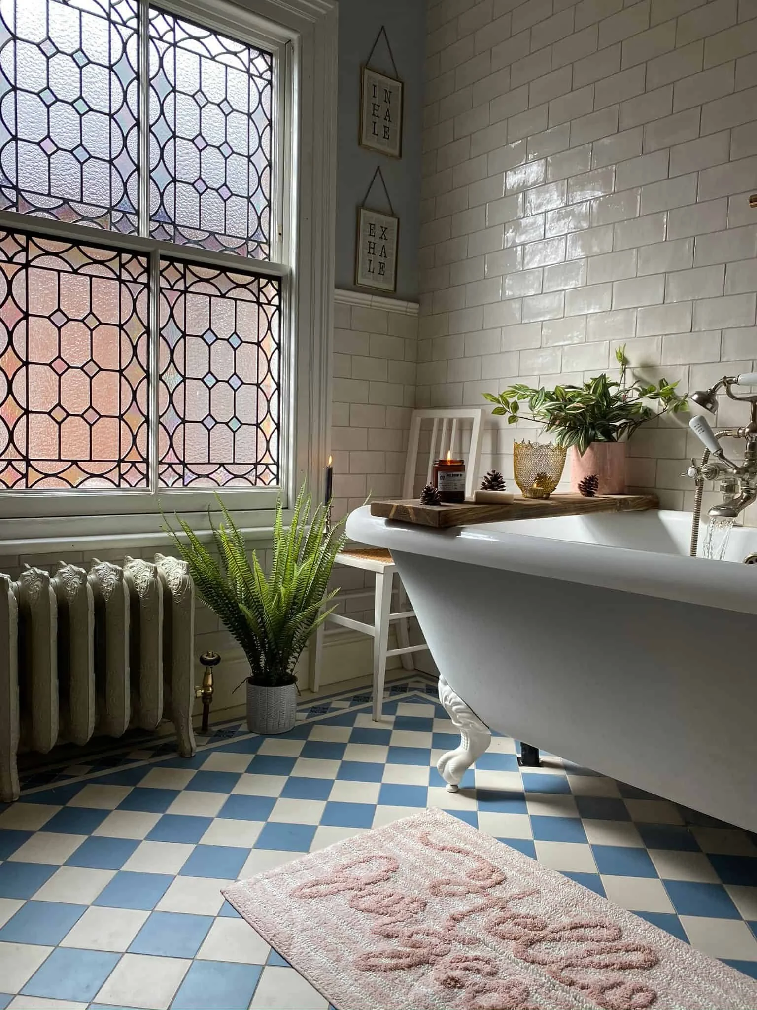 A Victorian bathroom renovation project with a clawfoot bathtub, patterned blue and white traditional tile floor, heritage shower fittings, a sash window with stained glass, and decorative interior design