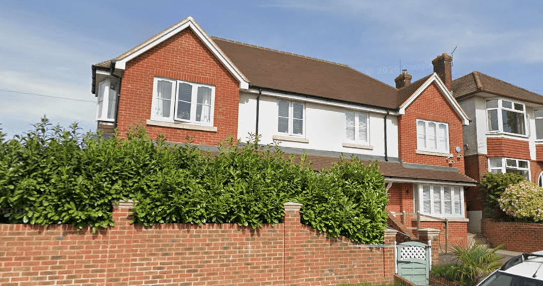 New build two-story semi detached timber frame houses with white window frames, clay tile roof, and a brick walls with landscaping in front.