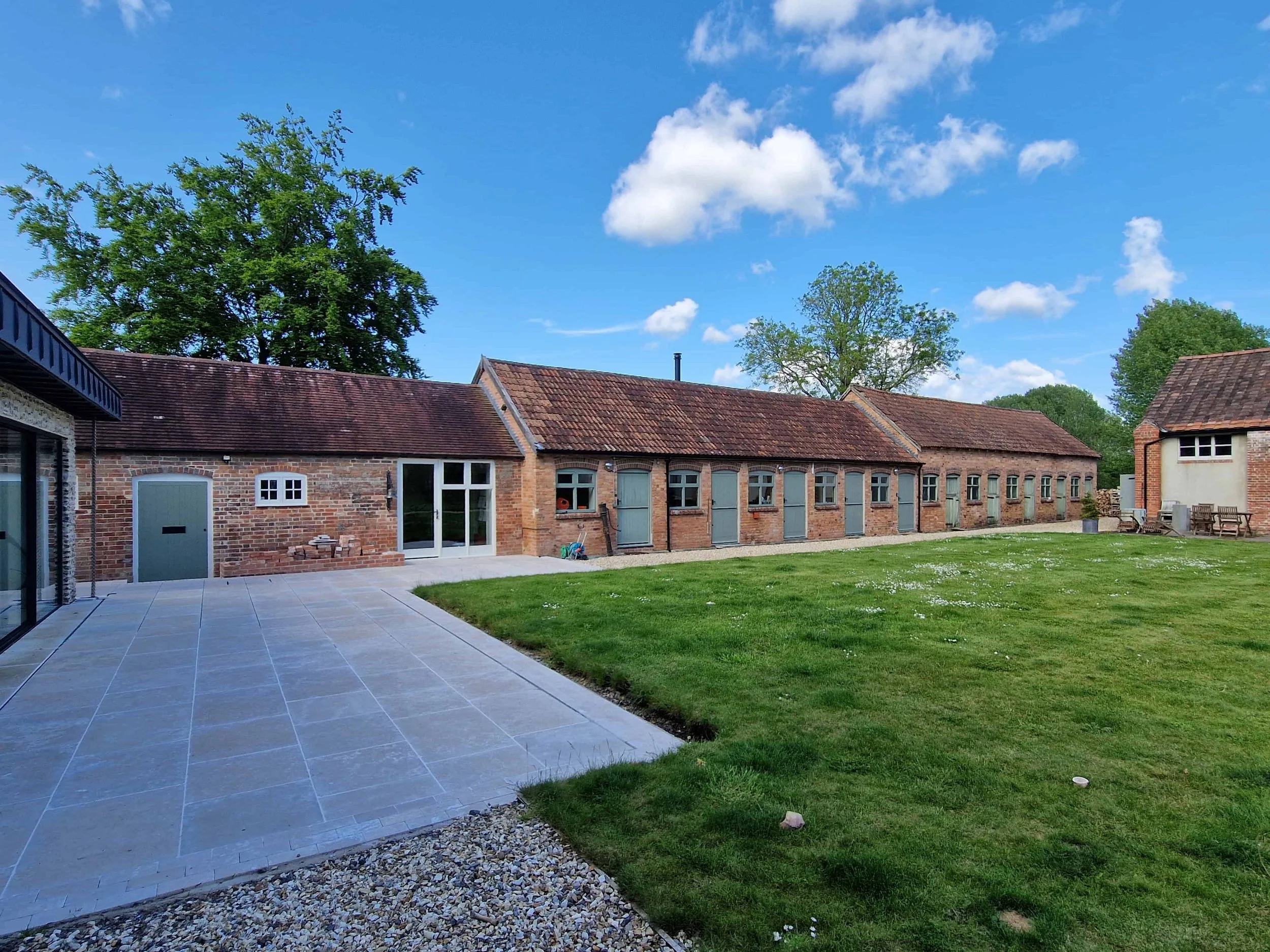 Historic listed courtyard of brick stables buildings with double roman tile roofs and timber windows and doors and brick arches to openings