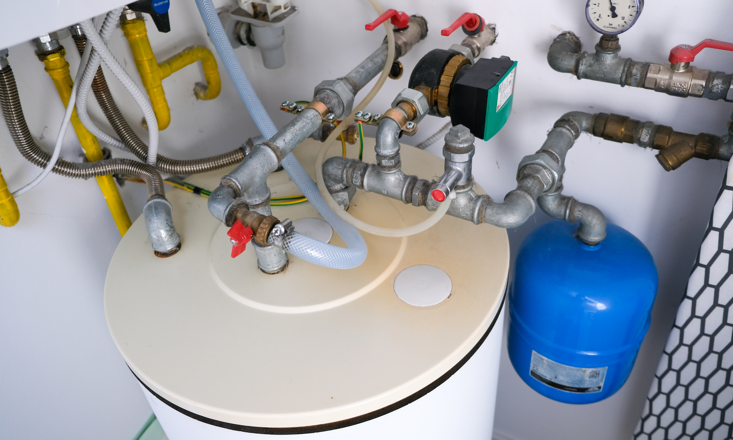 Plumbing and filtration system with various pipes, valves, a pressure gauge, and a blue tank.