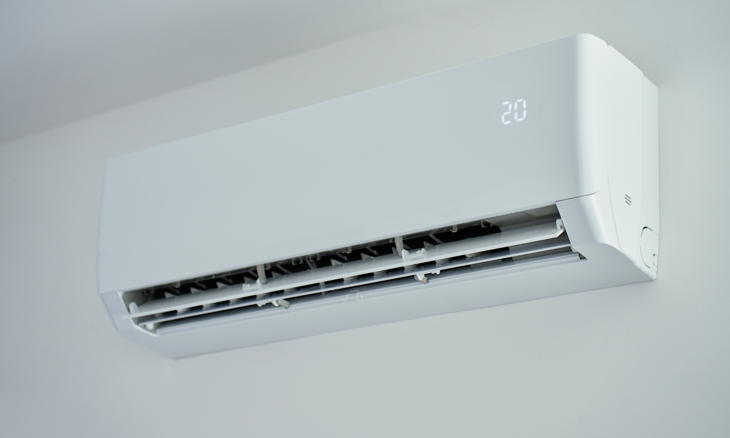 Wall-mounted white air conditioning unit displaying the temperature set at 20 degrees Celsius.
