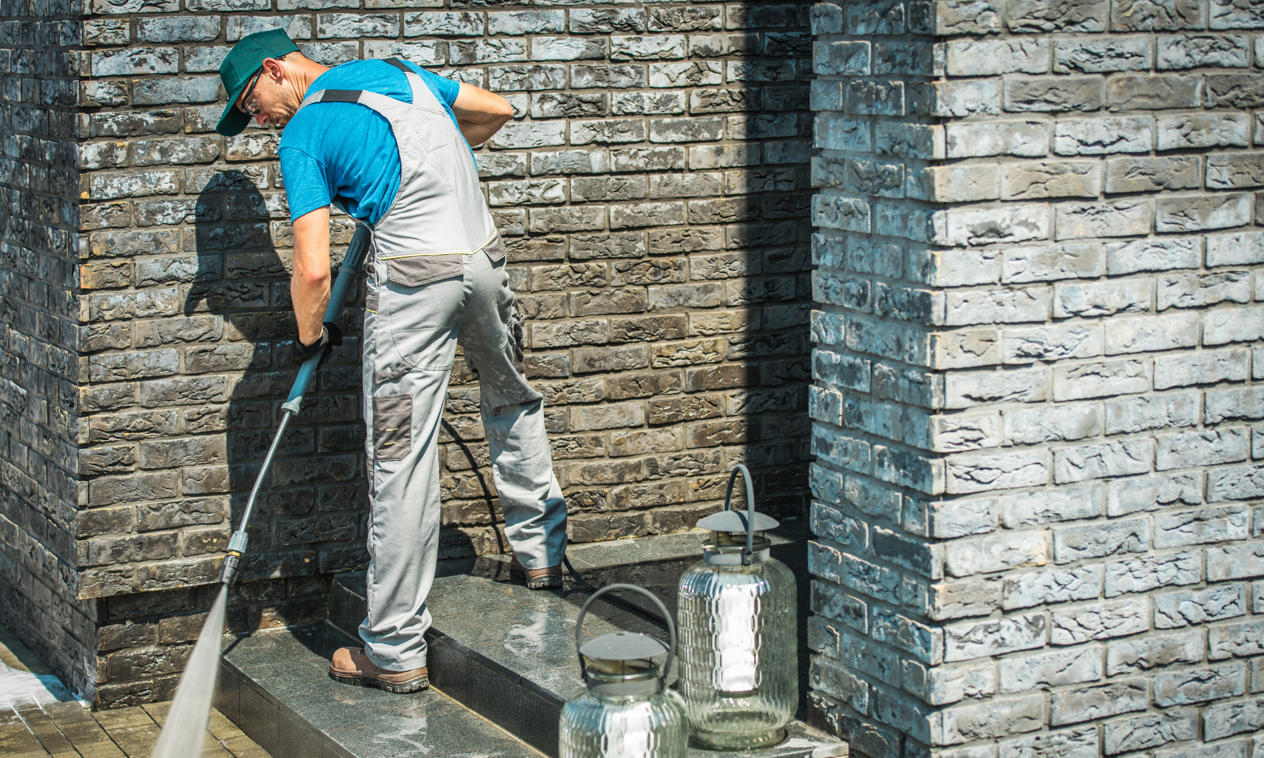 Man pressure washing exterior stone steps of a house