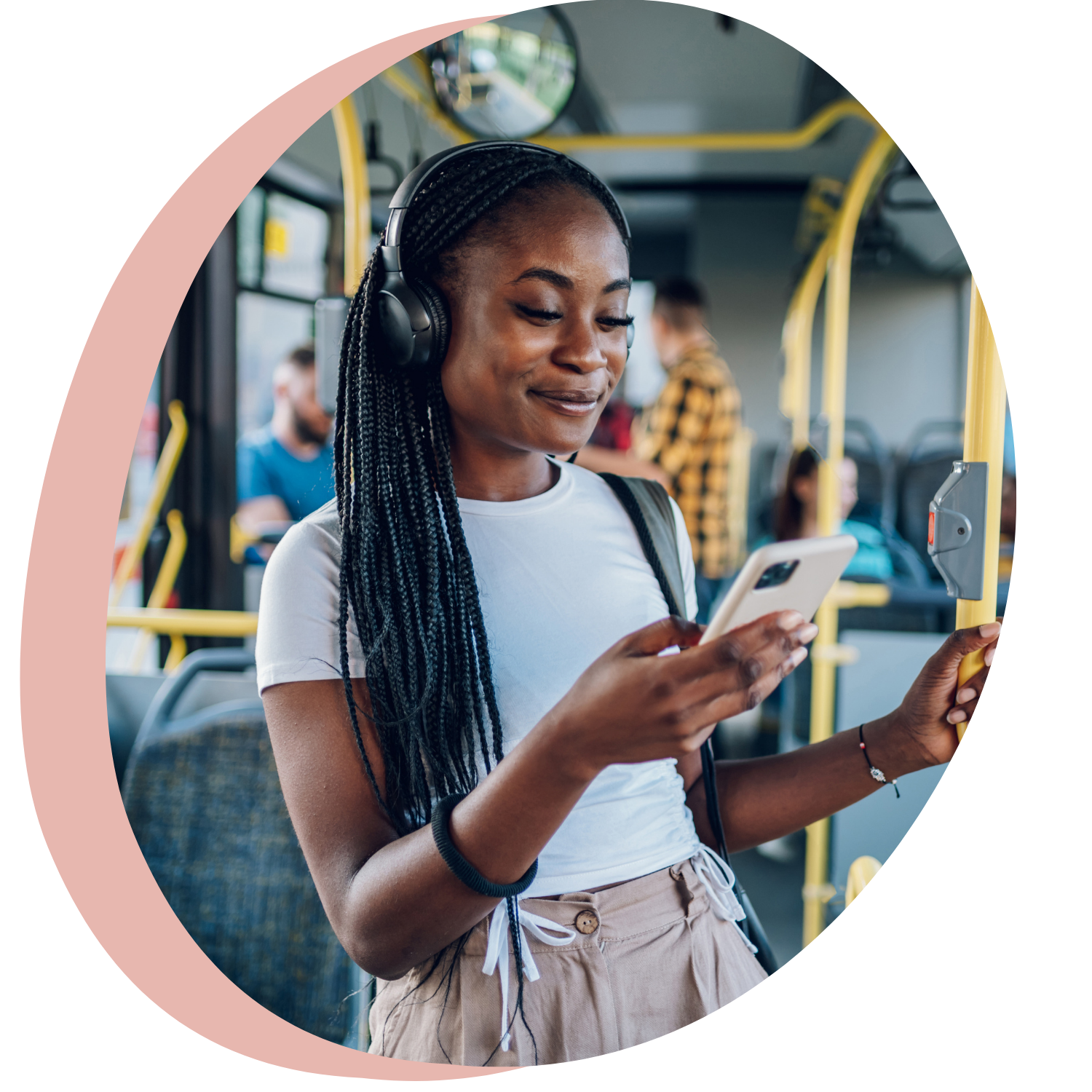 En kvinna som använder hörlurar och tittar på sin mobiltelefon på en buss.