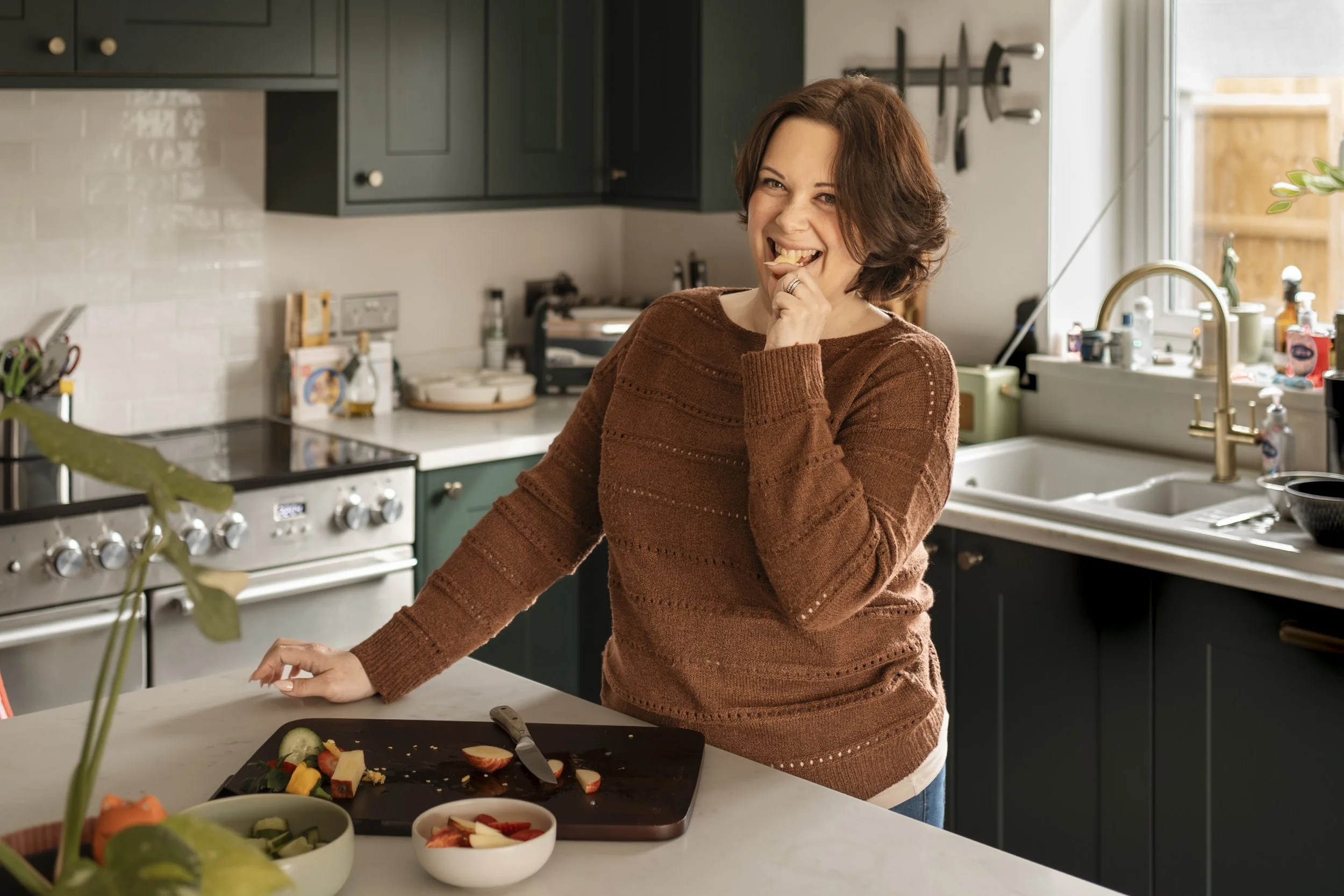Living room with beige sofa, decorative pillows, and a vase with white flowers on a wooden table, with two framed animal paintings on the wall—one of a goose and one of a deer with antlers.