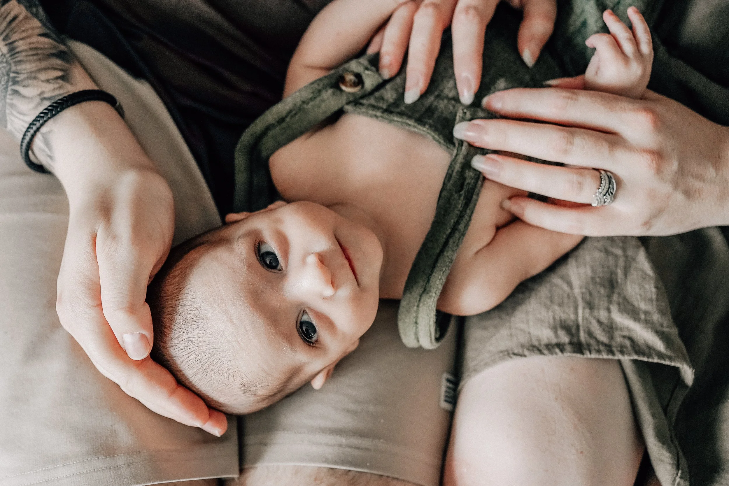 Close-up of a young boy lying on a person's lap, with the person gently holding and supporting his head and chest, both appearing relaxed.