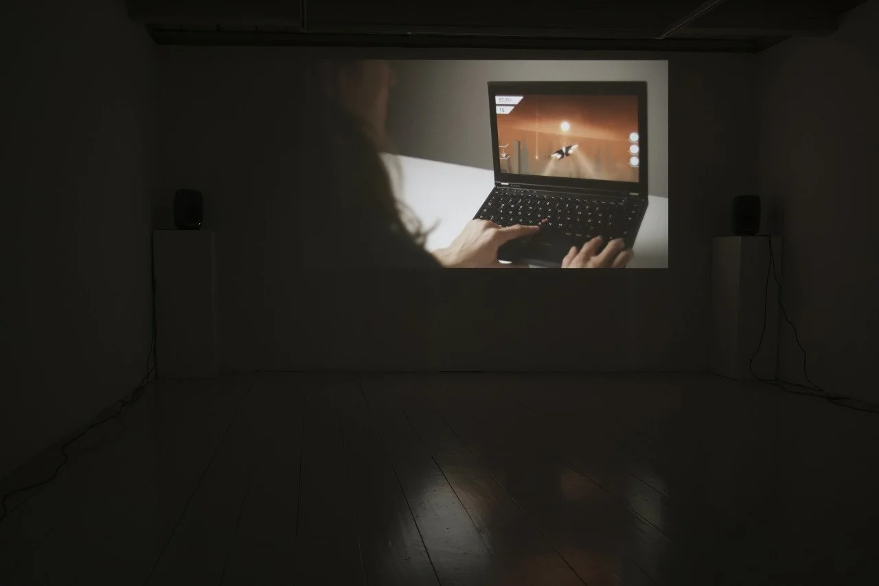 A person watching a movie or presentation on a large projection screen in a dark room, with two speakers on either side.