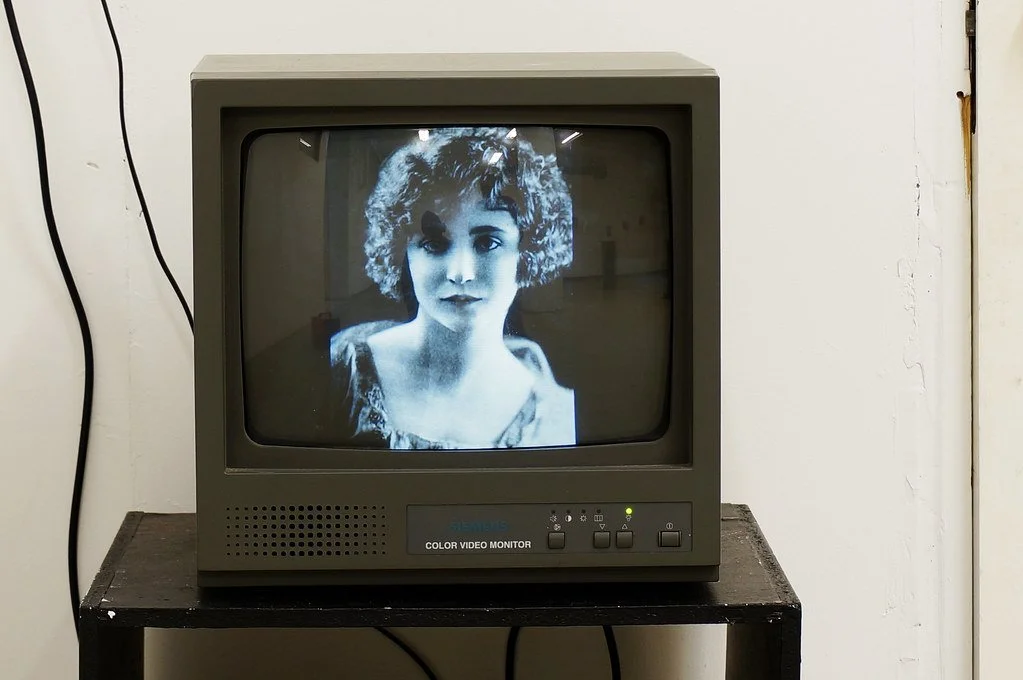 Old-fashioned black-and-white monitor displaying a woman's face with curly hair.
