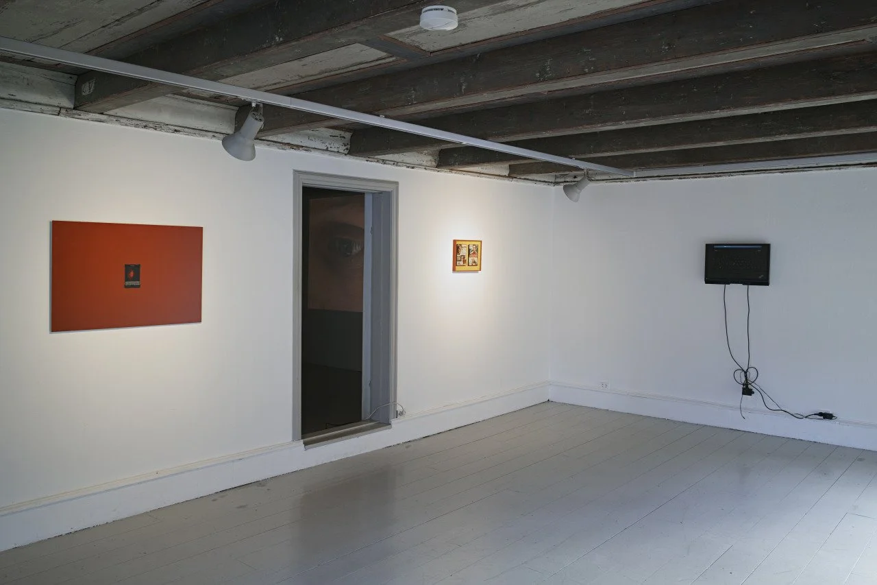 An art gallery showing three artworks on white walls, with a doorway leading to another room, a small TV mounted with cords hanging down, and track lighting on a wooden ceiling.