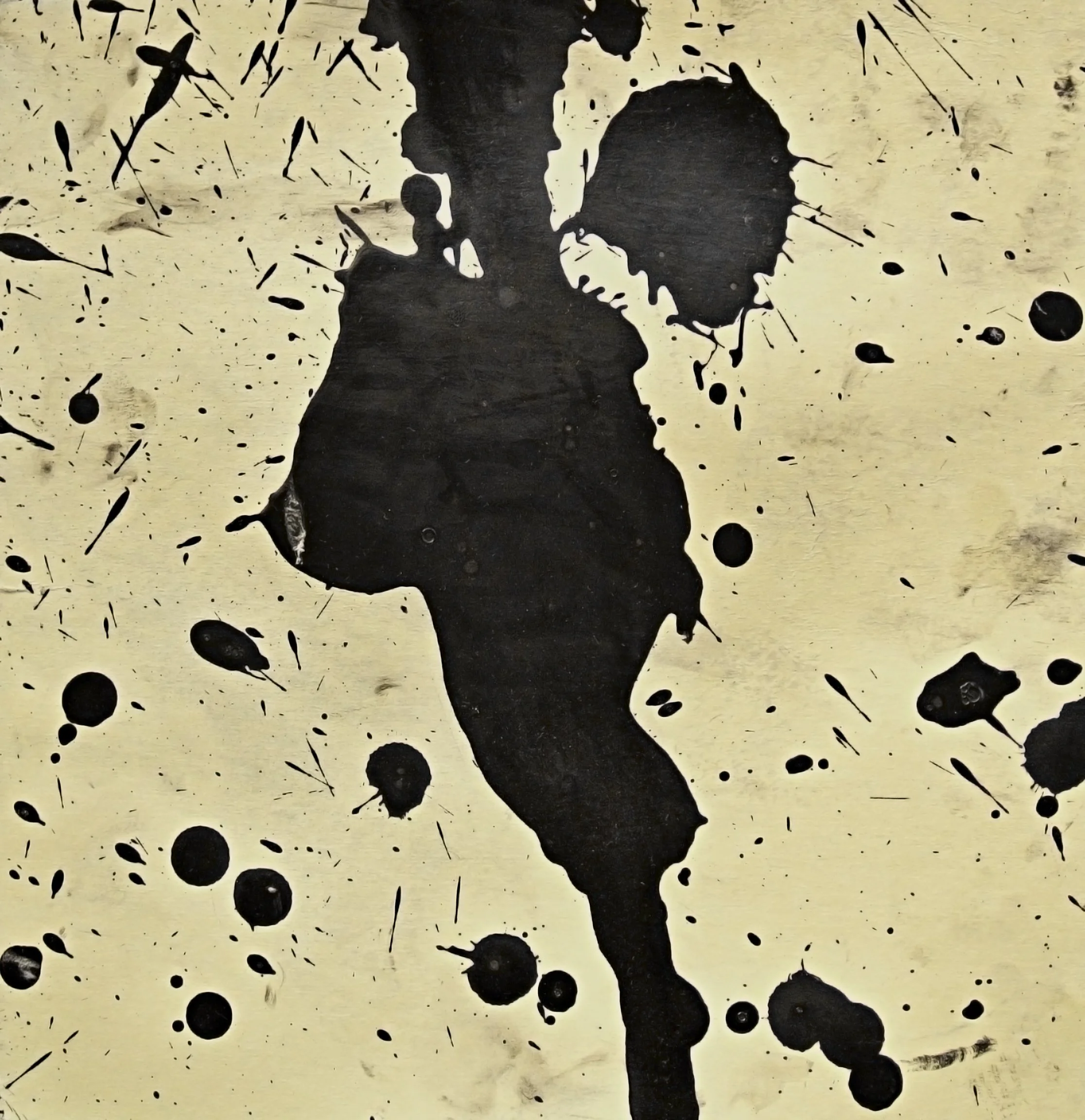 A black ink blot in the shape of a person, with the background splattered with more black ink splatters on a light surface.