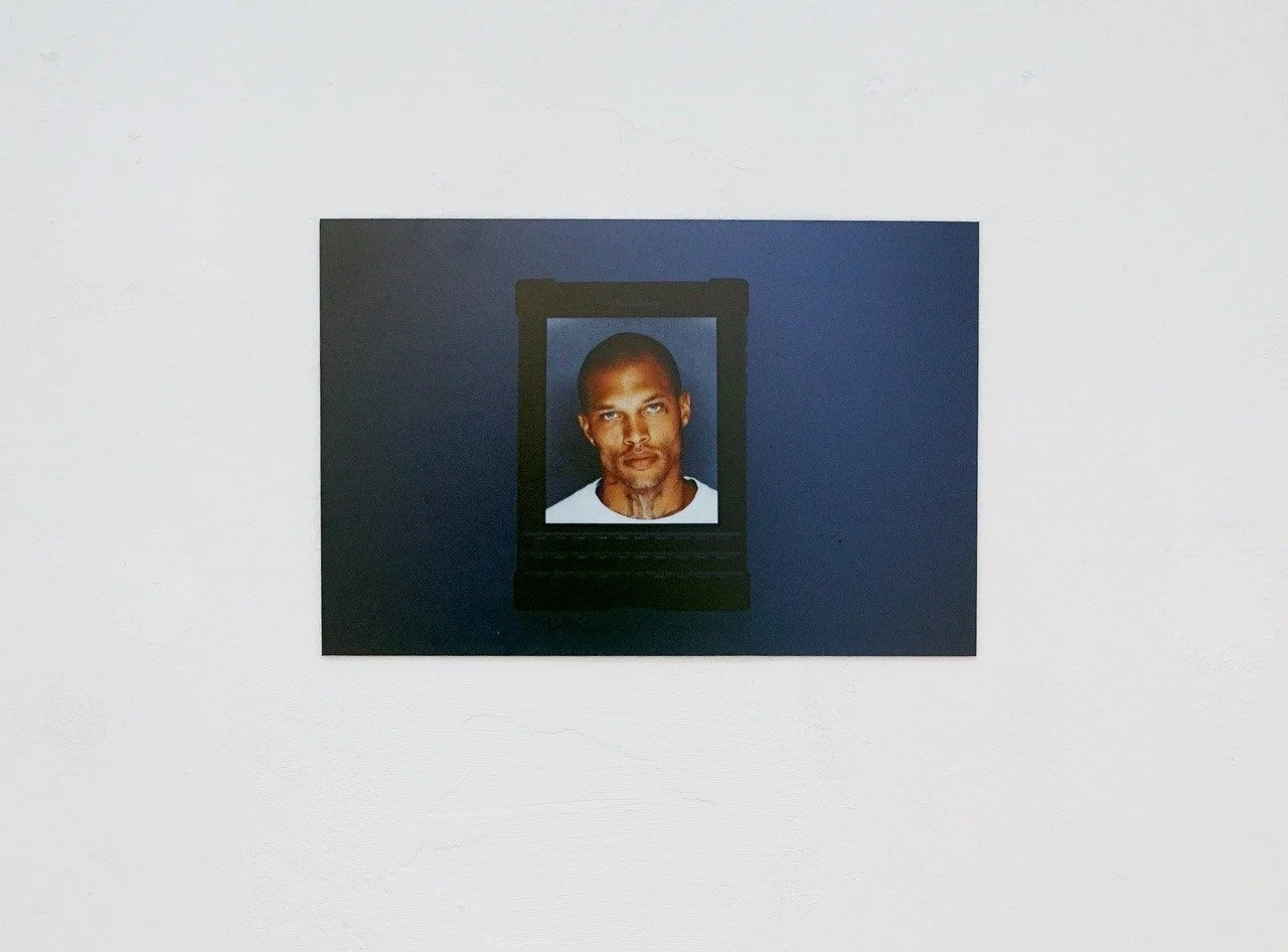 A portrait of Jeremy Meeks displayed on a BlackBerry Passport screen, mounted on a wall with a dark background. Space 4235, Genova.