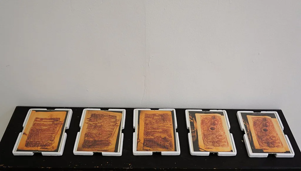 Five tarot card decks placed face down on a black table against a plain white wall.